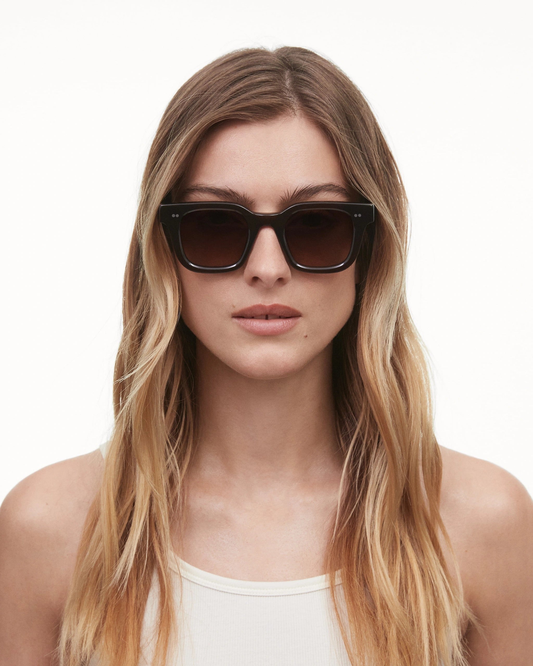 Unisex model wearing 04 Core Brown Sunglasses with dark lenses and a stylish frame.