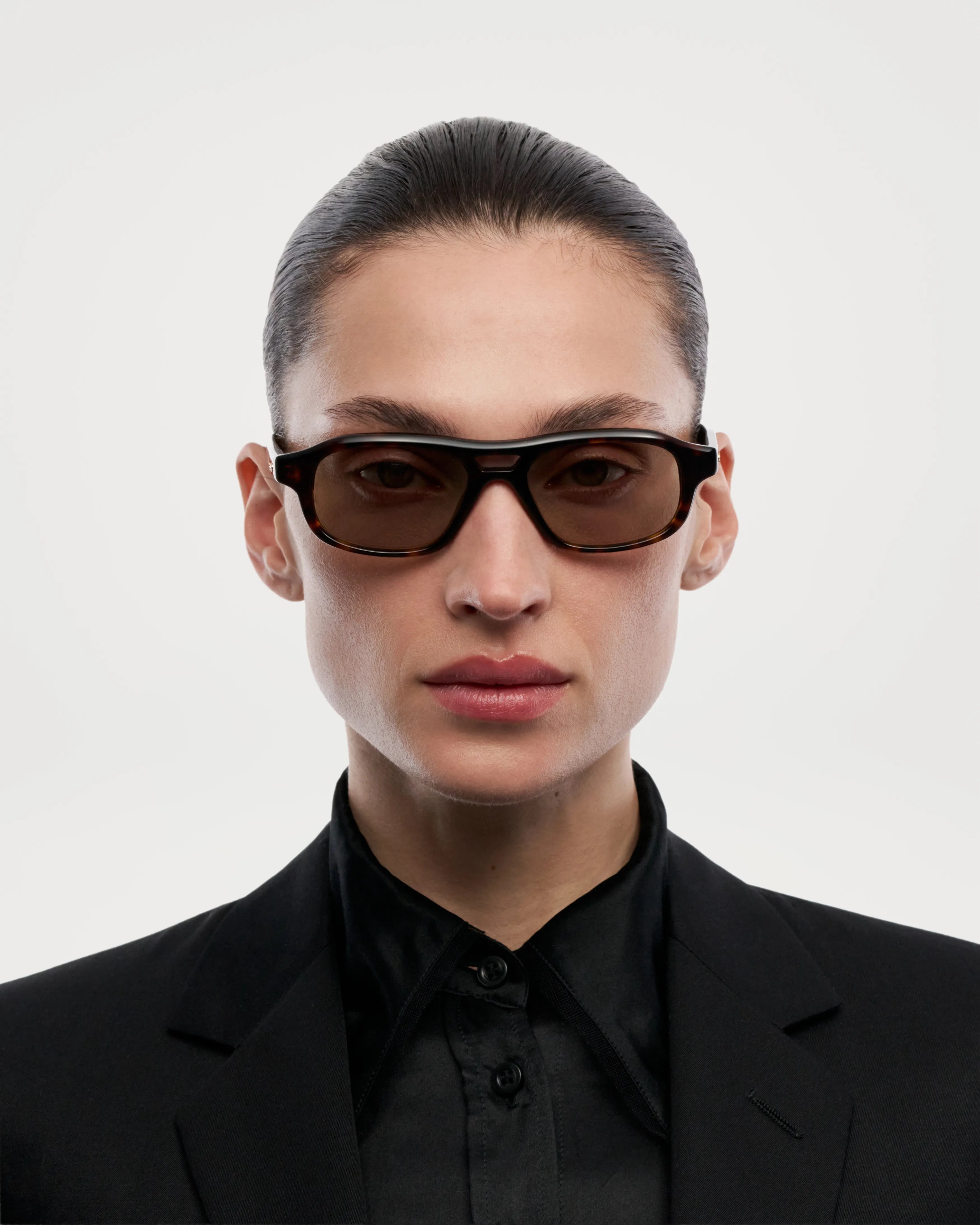 Eli Terra Tortoise Sunglasses being modeled by a person in a black suit against a neutral background.