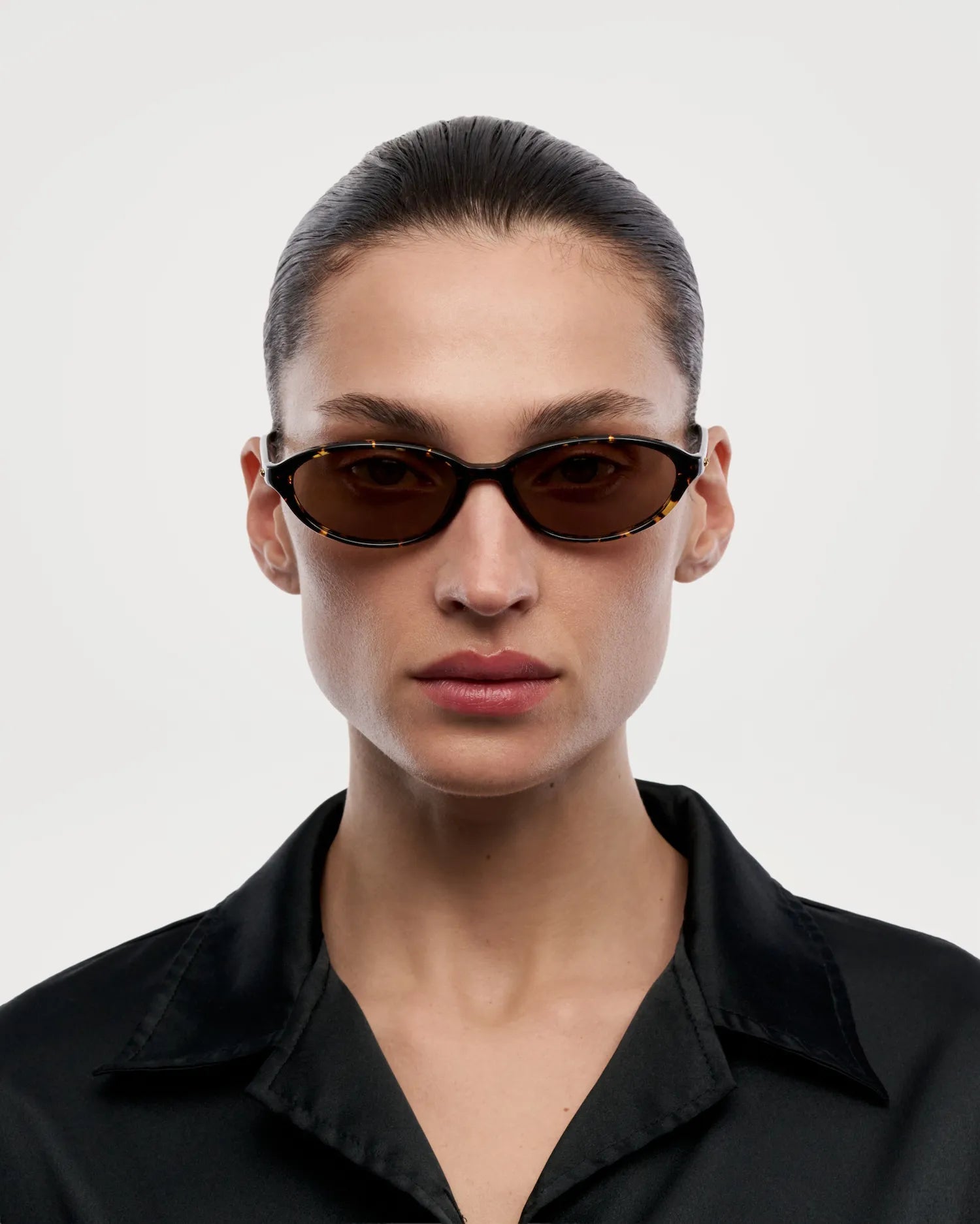 Ellipse Feral Tortoise Sunglasses modeled by a woman wearing a black outfit, showcasing stylish design and fit.