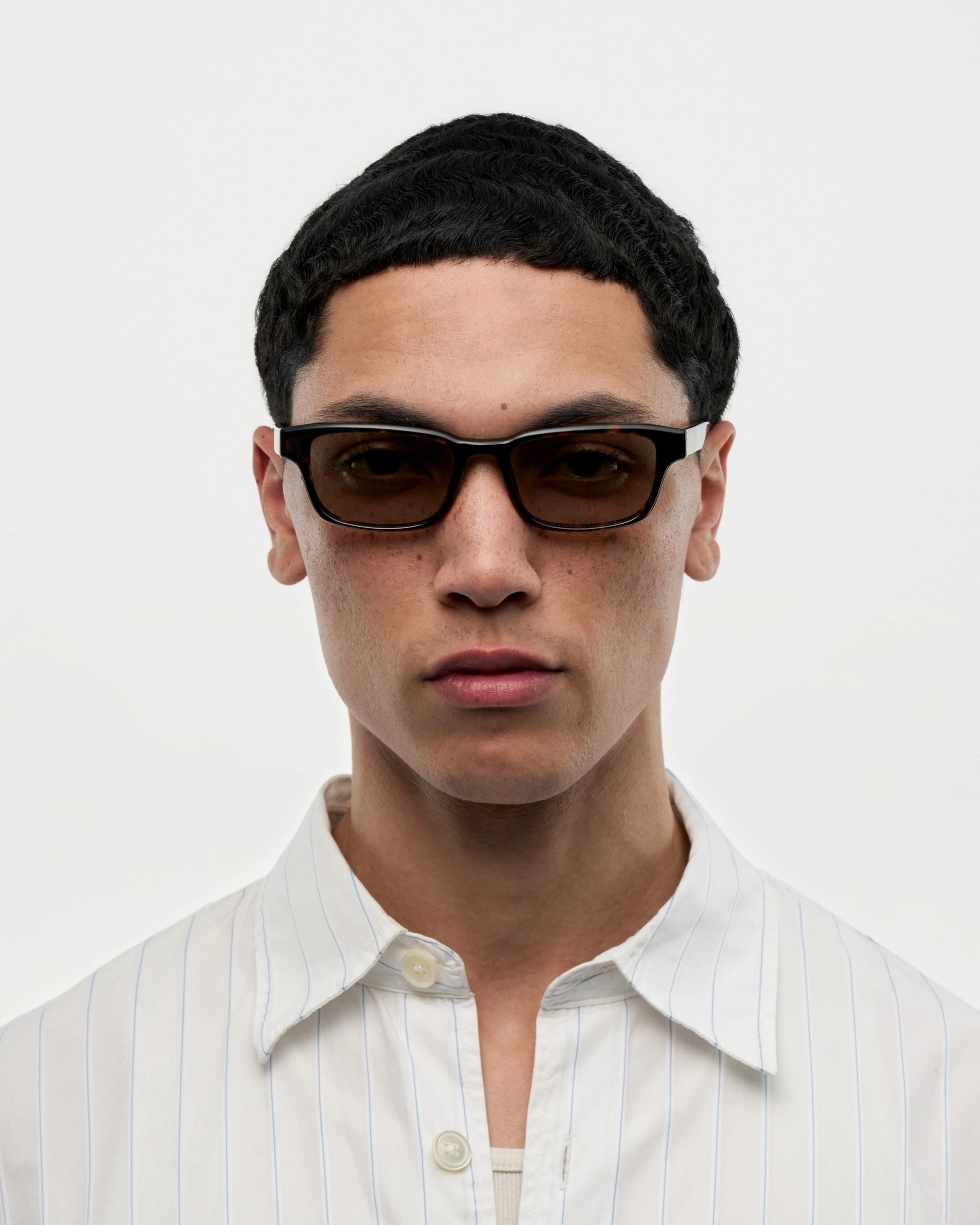 A model wearing Kasi Terra Tortoise Sunglasses, showcasing a stylish look with a modern shirt.