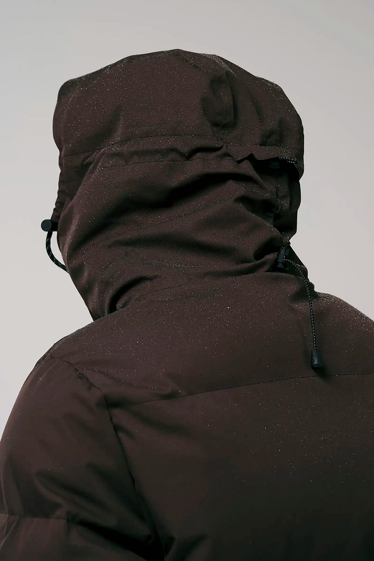 Back view of the Bayu Black Coffee Coat featuring a hood and waterproof fabric.