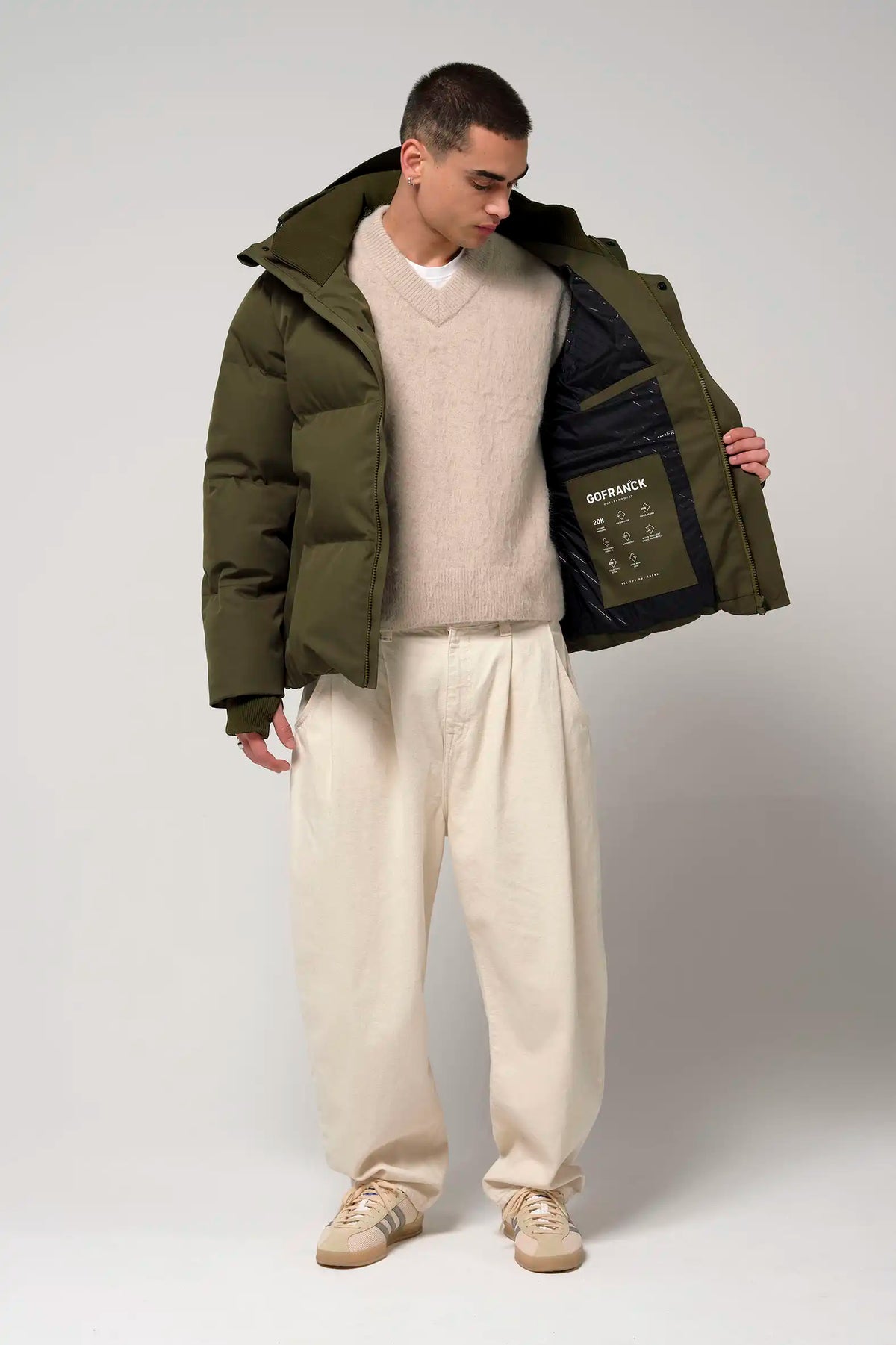 Model wearing Bayu Dark Olive Green Coat with a sweater and pants showcasing its interior features.