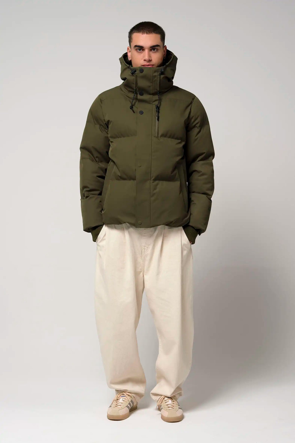 Model wearing the Bayu Dark Olive Green Coat, a waterproof and windproof puffer jacket with biodegradable insulation.