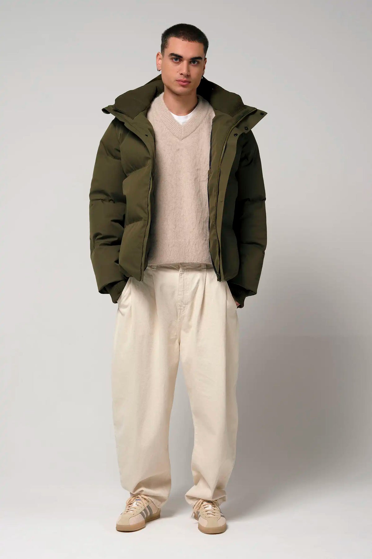 Model wearing Bayu Dark Olive Green Coat over a beige sweater and cream pants, showcasing a stylish winter outfit.