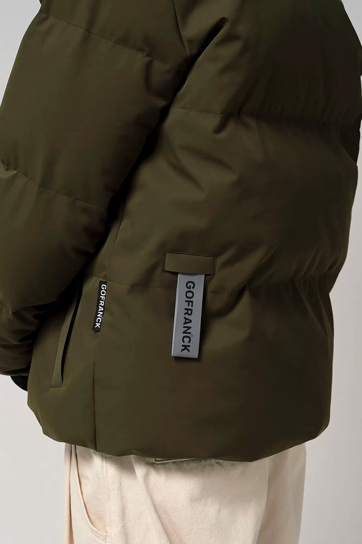 Bayu Dark Olive Green Coat displayed, showcasing side view and branding detail, perfect for outdoor activities.