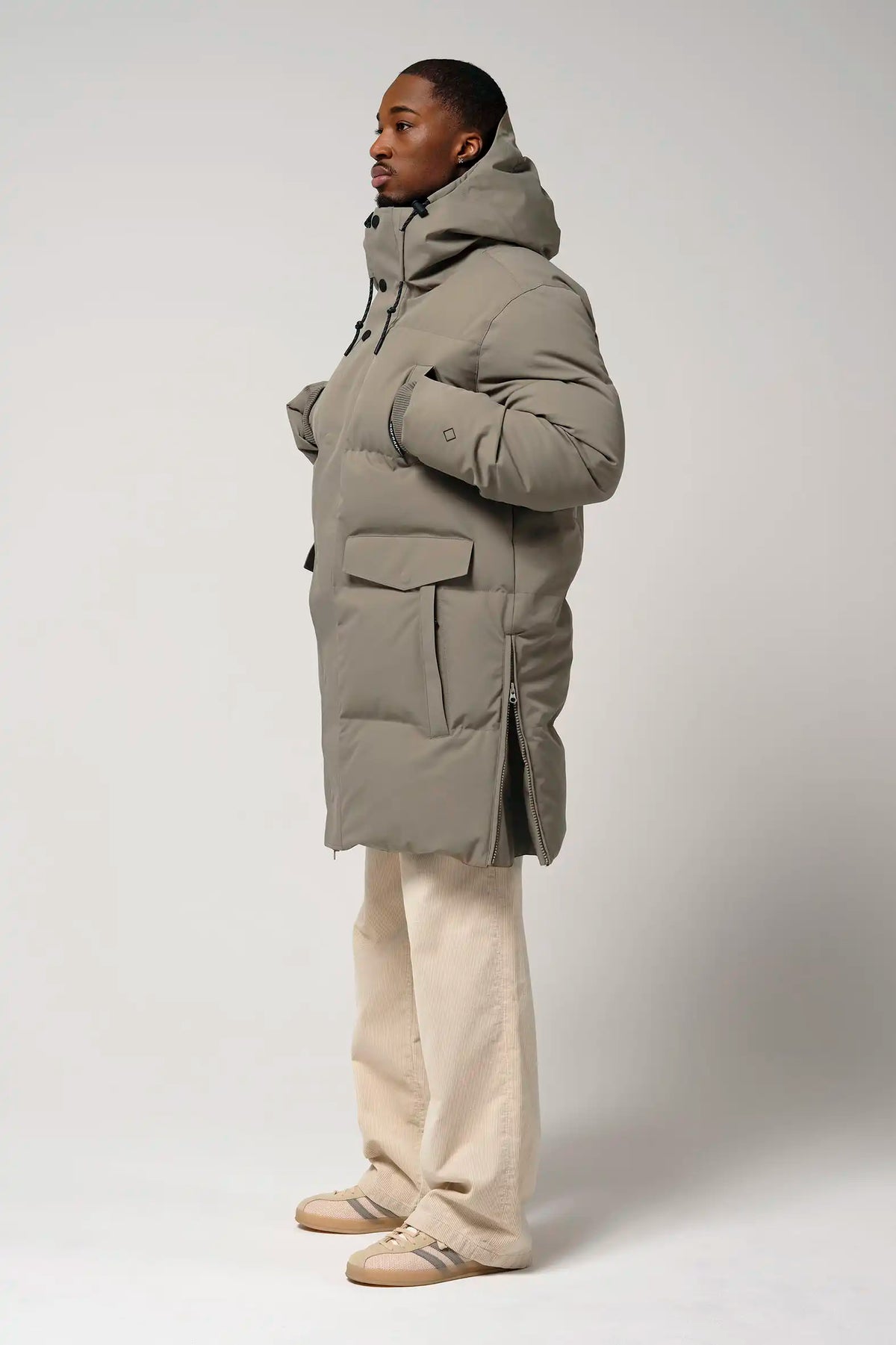 Model wearing Climate Timber Wolf Grey Coat, featuring side zippers and multiple pockets.