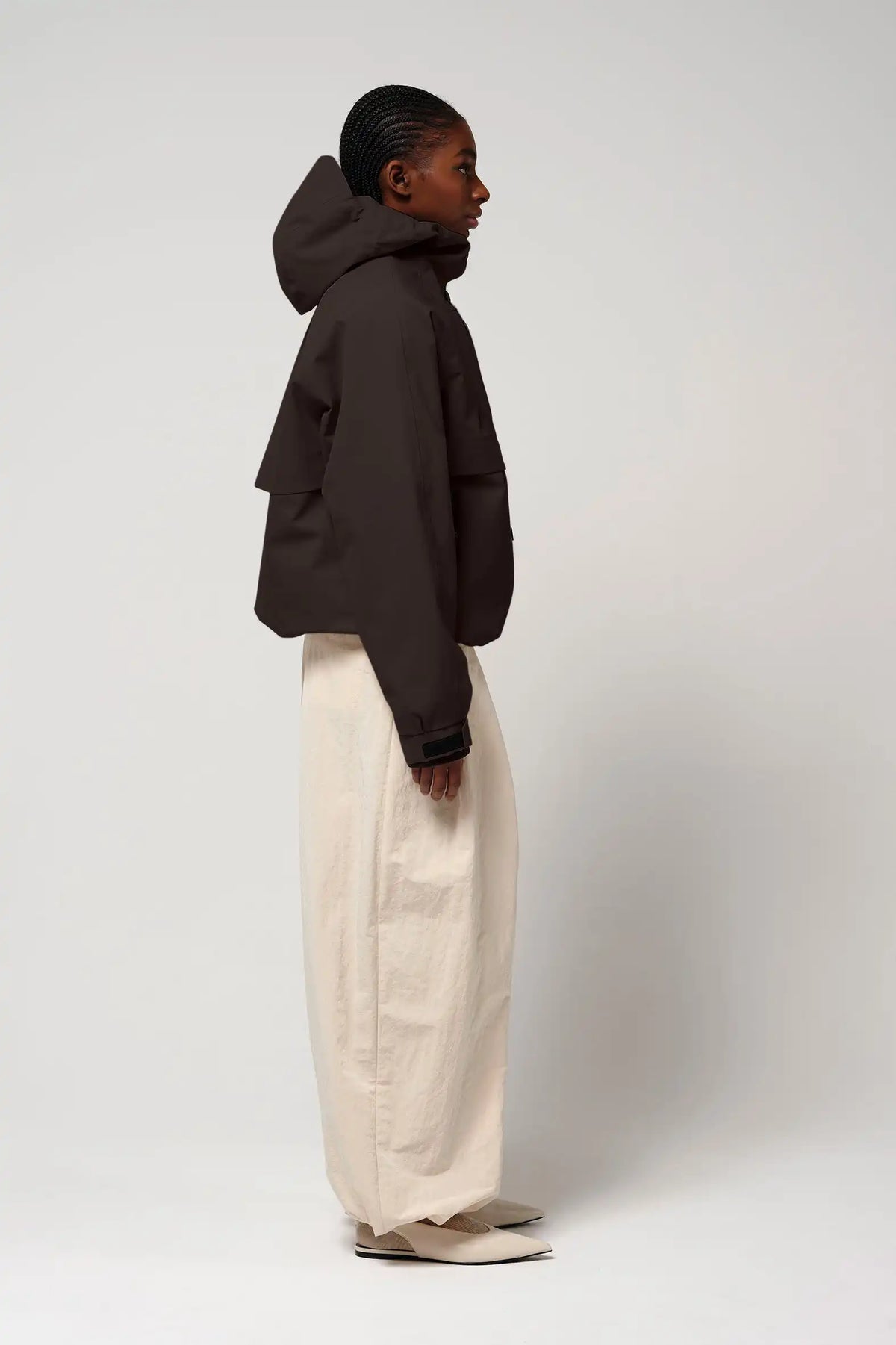 Profile view of a model wearing the Guthrie Black Coffee Coat in black, showcasing its waterproof and windproof features.
