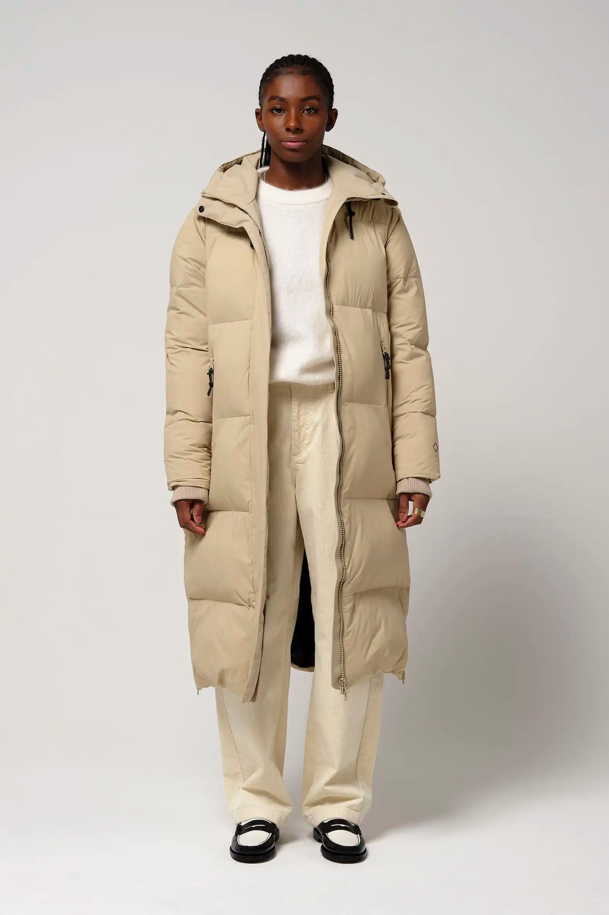 Model wearing Tsunami Fields of Rye Beige Coat, a lightweight waterproof puffer coat with a stylish design.