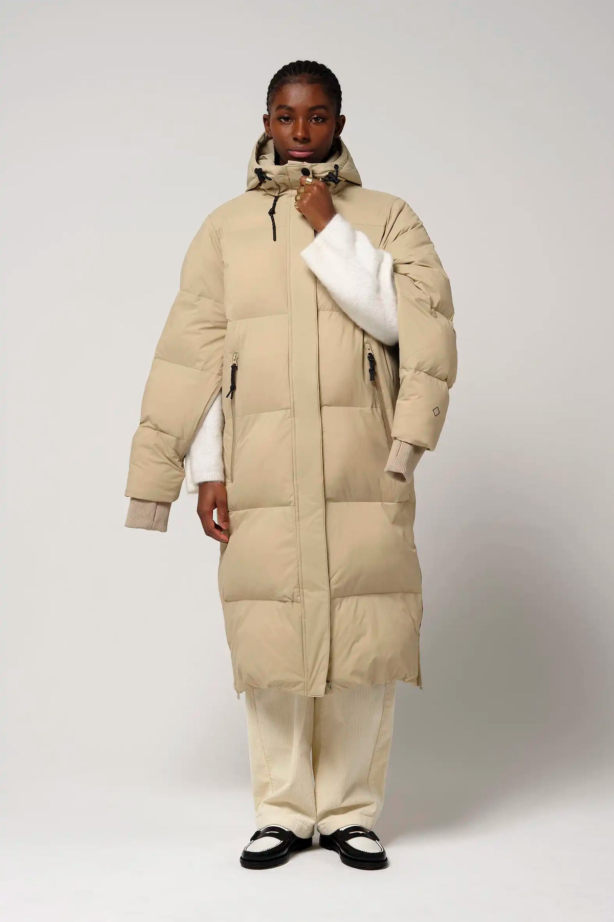 Model wearing Tsunami Fields of Rye Beige Coat, a lightweight waterproof puffer coat with stylish features.