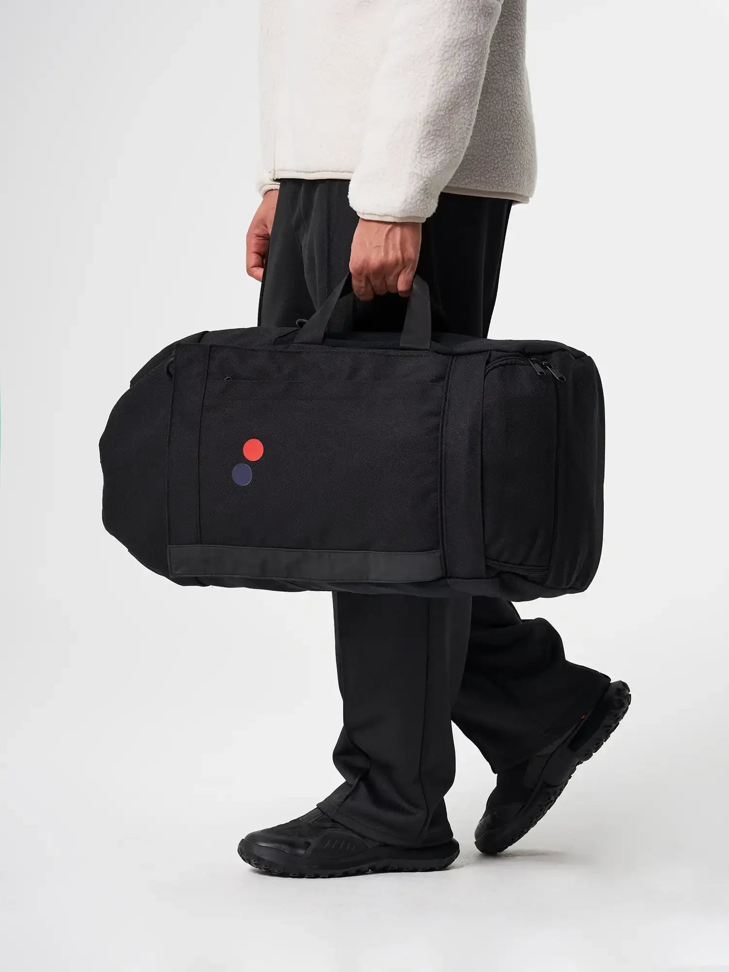 Person carrying a Blok Large Licorice Black Backpack in black, showcasing its durable design and functionality.