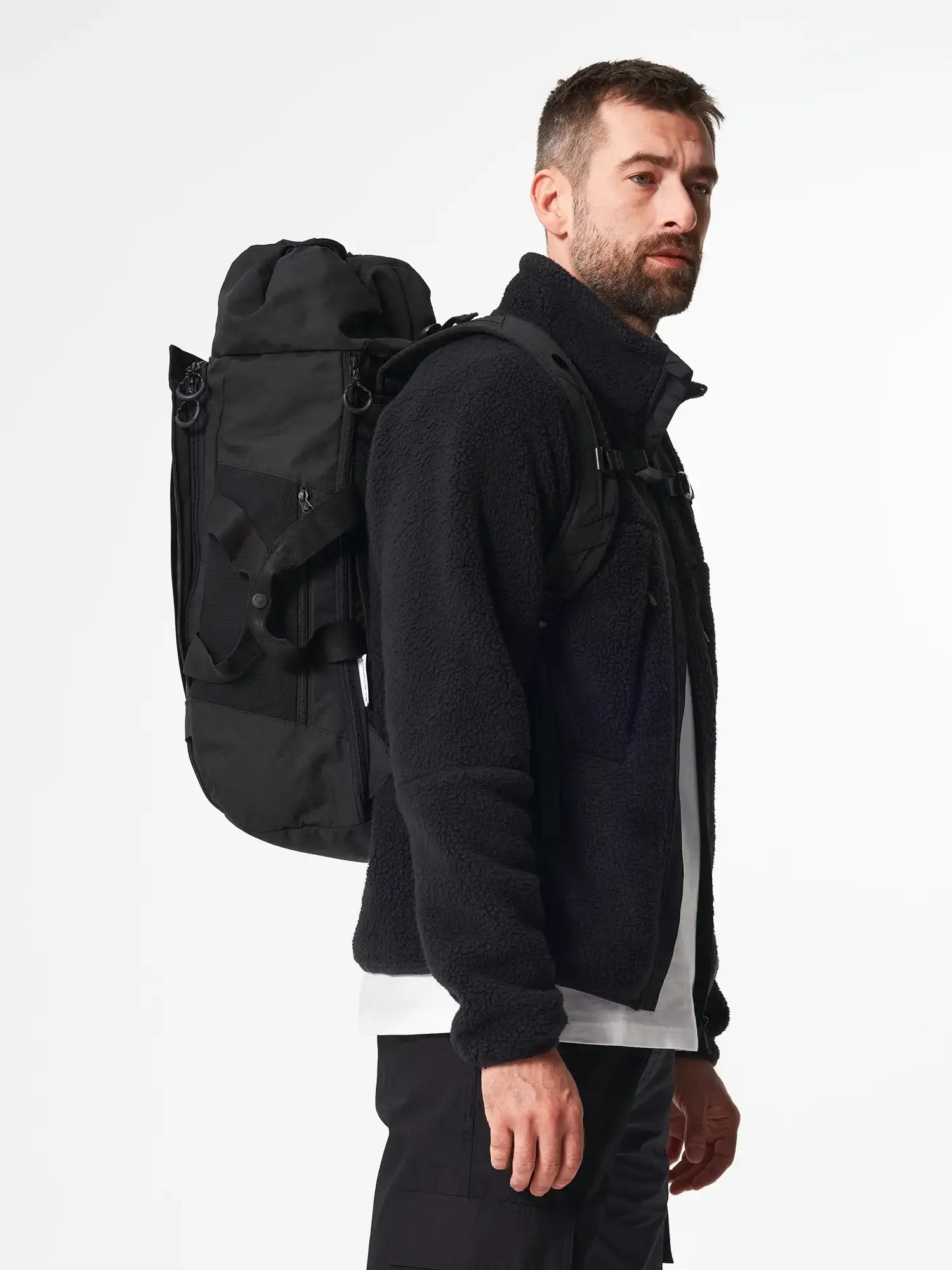 Man wearing Blok Large Rooted Black Backpack, showcasing its sleek design and practical features.