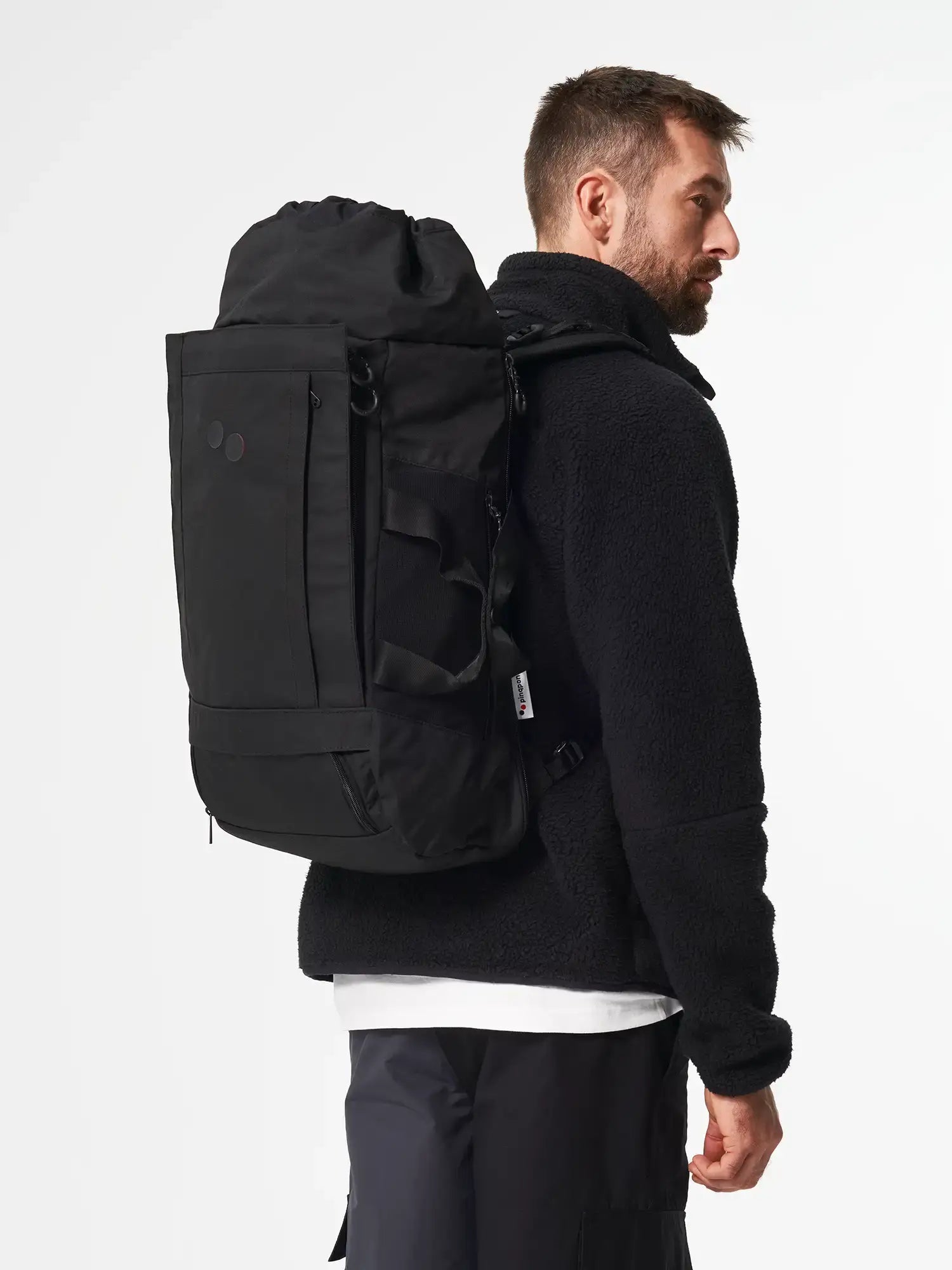 Man wearing Blok Large Rooted Black Backpack, showcasing its sleek design and comfortable fit.