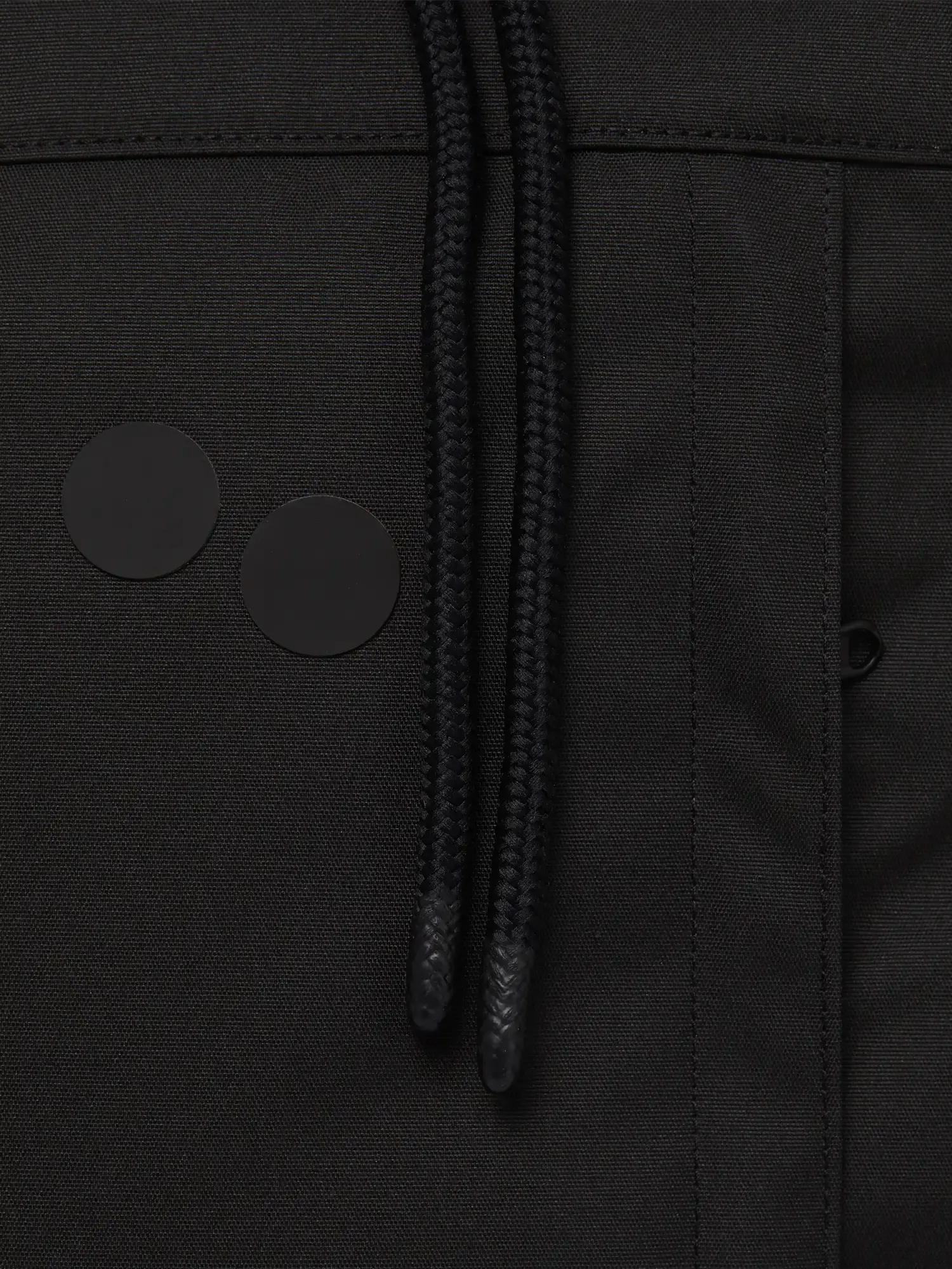 Close-up of the Blok Large Rooted Black Backpack's zipper and drawstrings detail.