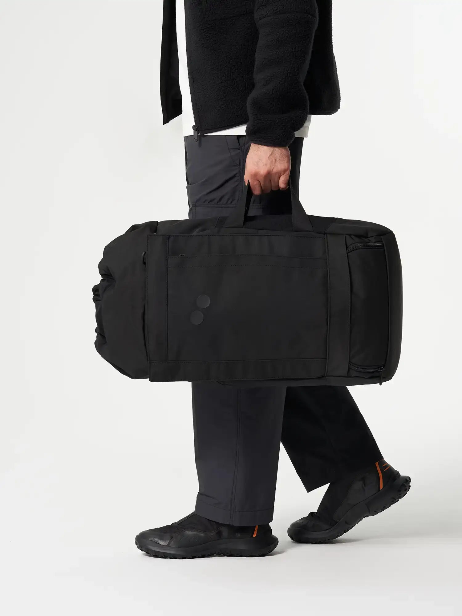 Man carrying the Blok Large Rooted Black Backpack in a stylish and modern outfit.