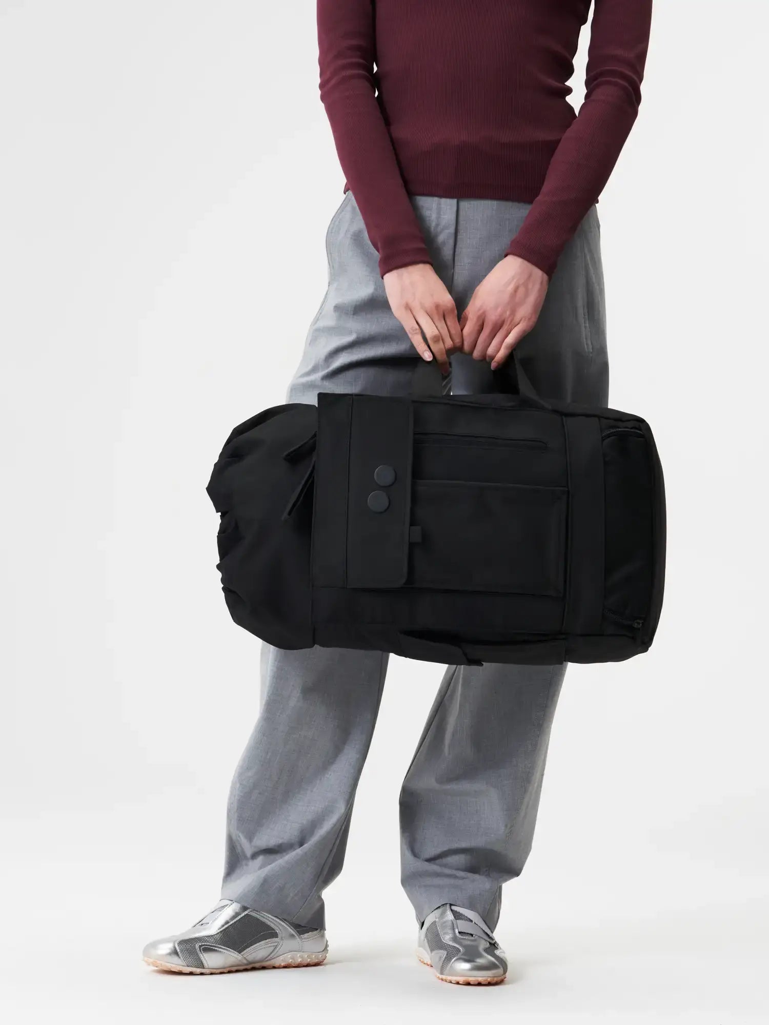 Blok Medium Construct Black Backpack shown being held in hands, featuring multiple compartments and adjustable straps.