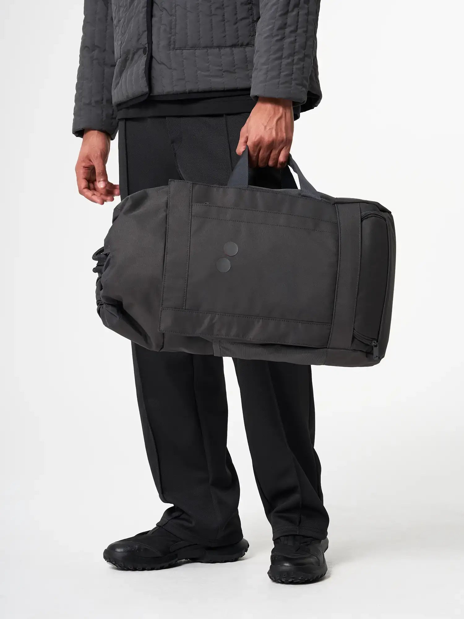 Blok Medium Deep Anthra Backpack held by a person, showcasing its water repellent design and storage features.