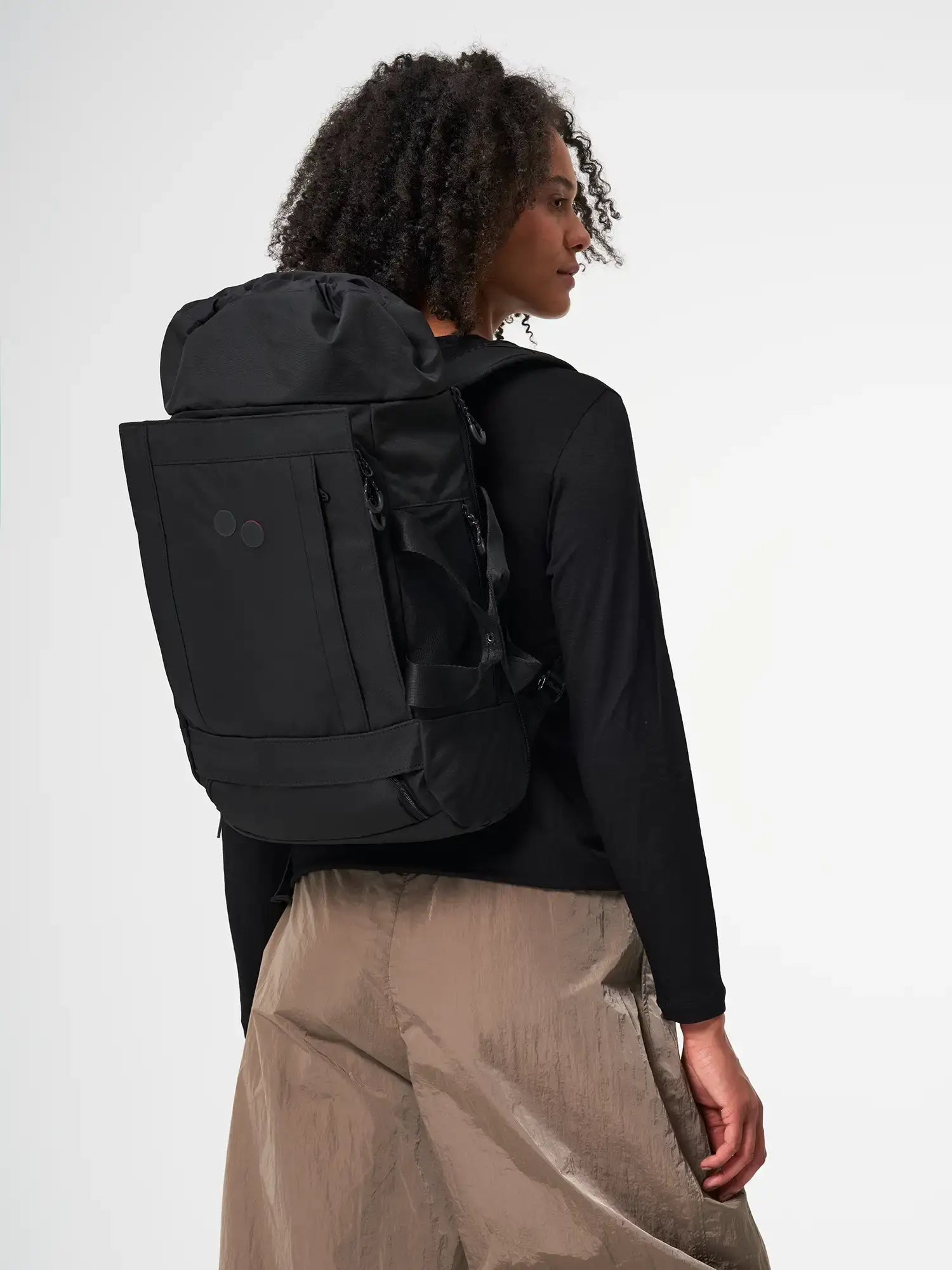 Blok Medium Rooted Black Backpack worn by a woman, showcasing its stylish design and functional features.