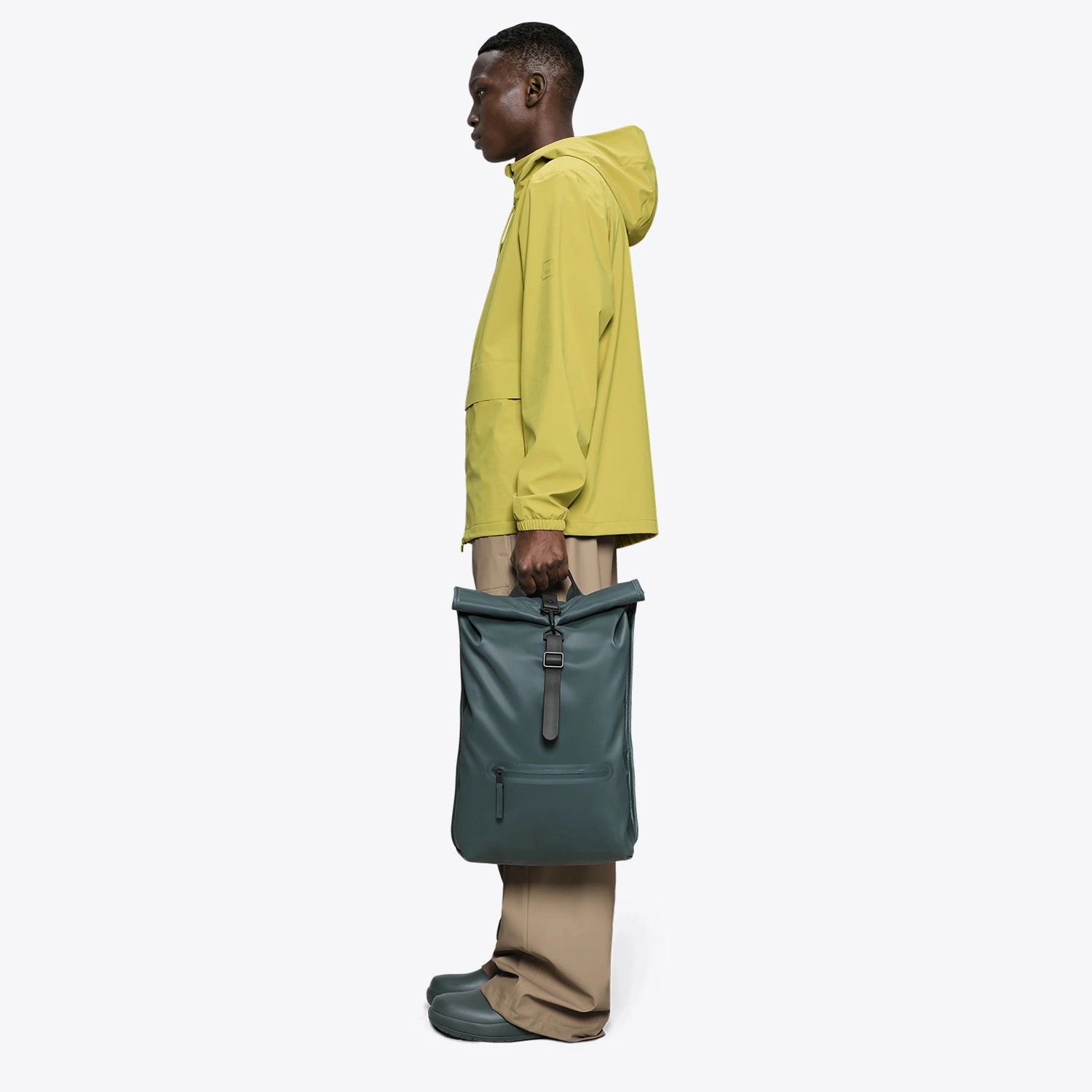 Rolltop Rucksack Mystique Backpack showcased by a person in a yellow rain jacket, demonstrating a stylish side profile.