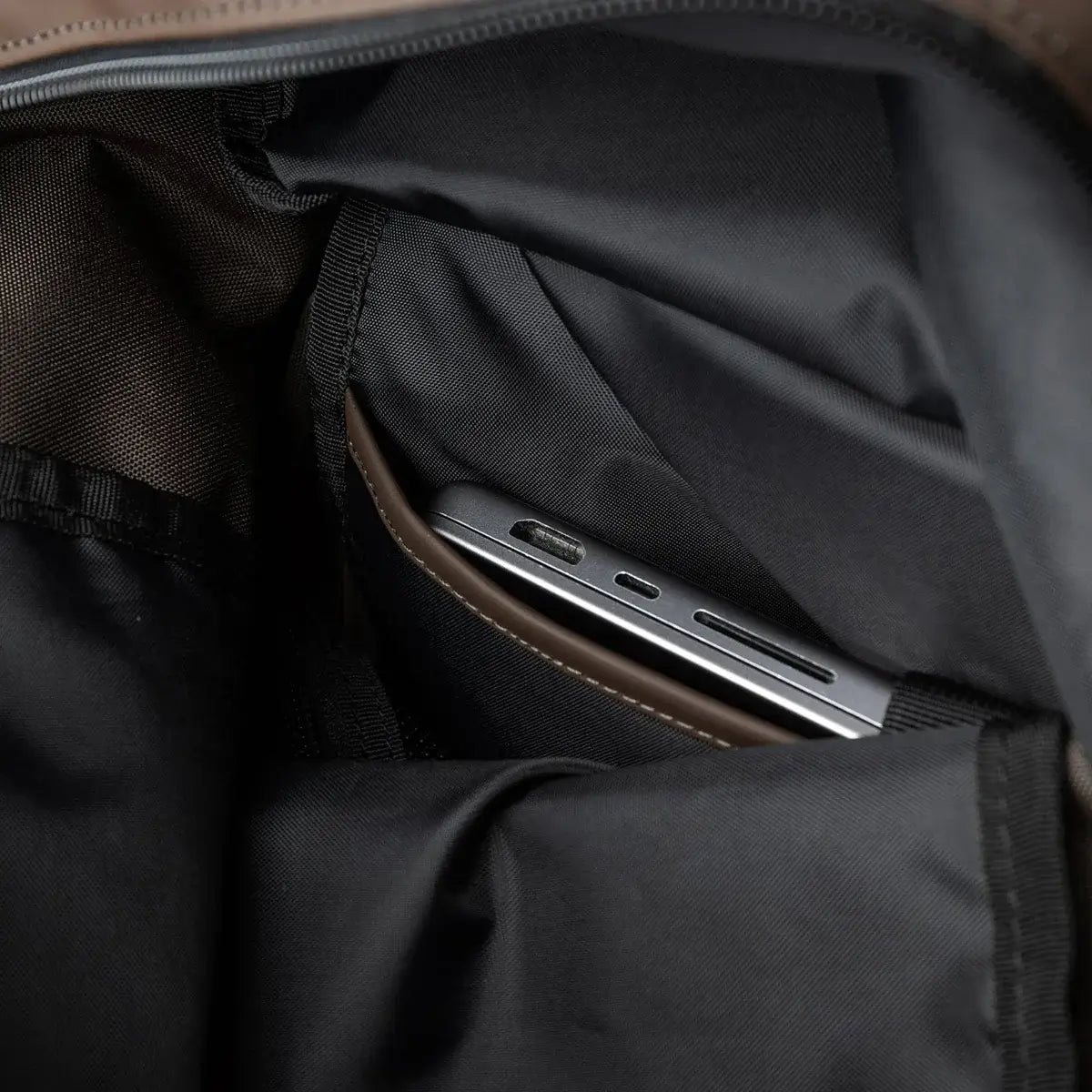 Interior view of Stream Rolltop Backpack L Brown Backpack with a smartphone in the pocket.