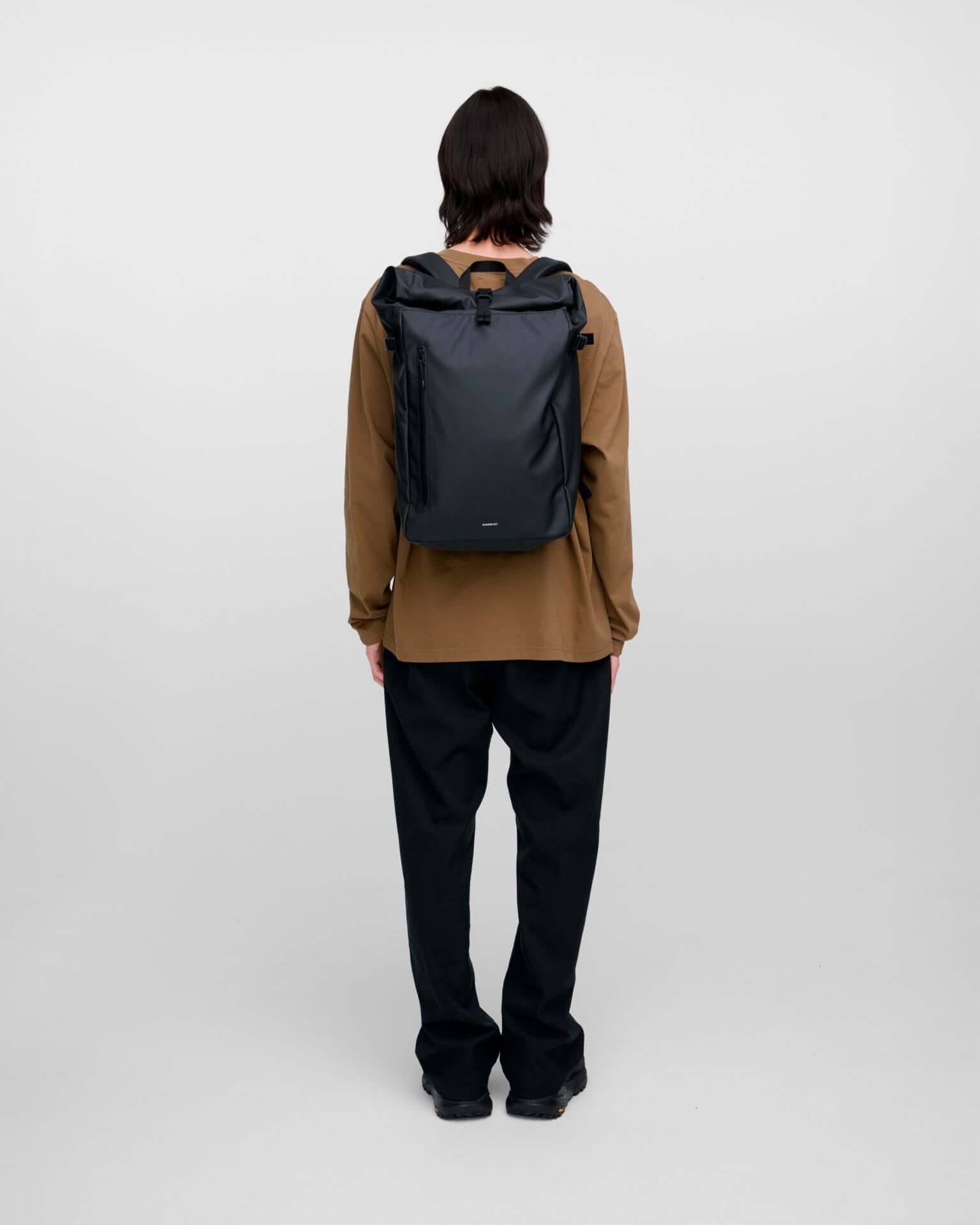Stream Slim Rolltop L Black Backpack on a person from behind, showcasing its sleek design and waterproof material.