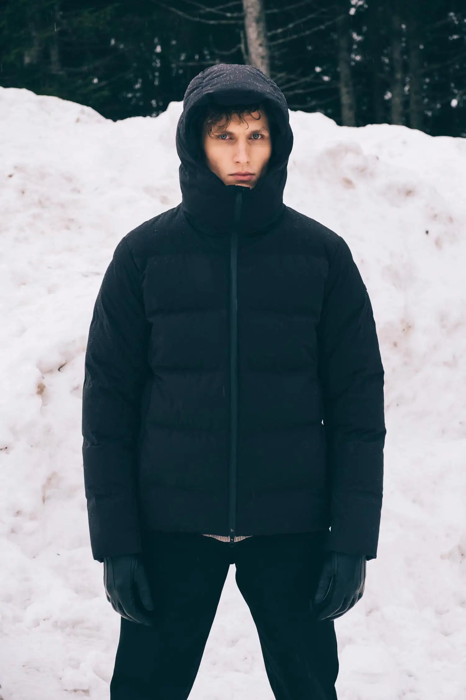 Man wearing the Torrent II Onyx Coat, a waterproof insulated jacket, standing in snowy landscape.