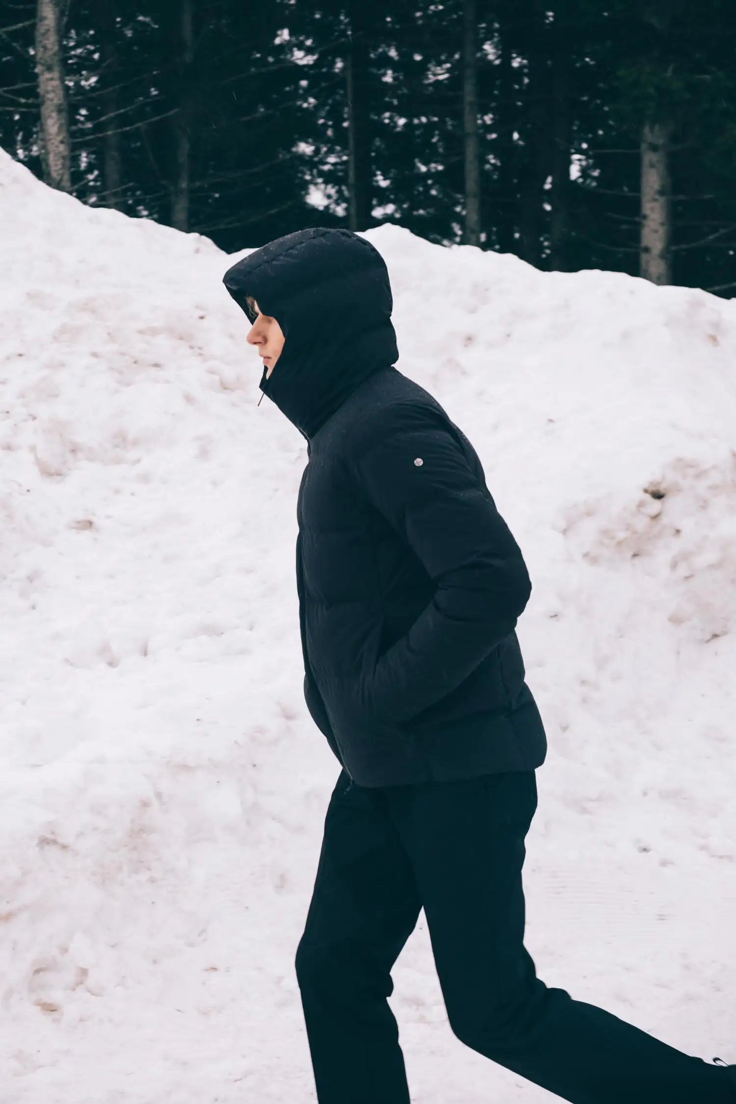 Person wearing the Torrent II Onyx Coat walking in snowy landscape.
