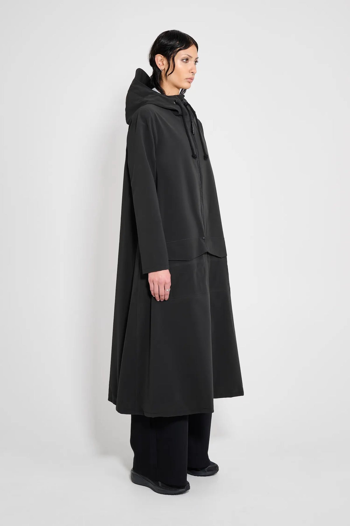 Mosebacke Long Patch Black Raincoat displayed on a model, showcasing its A-line silhouette and adjustable hood.