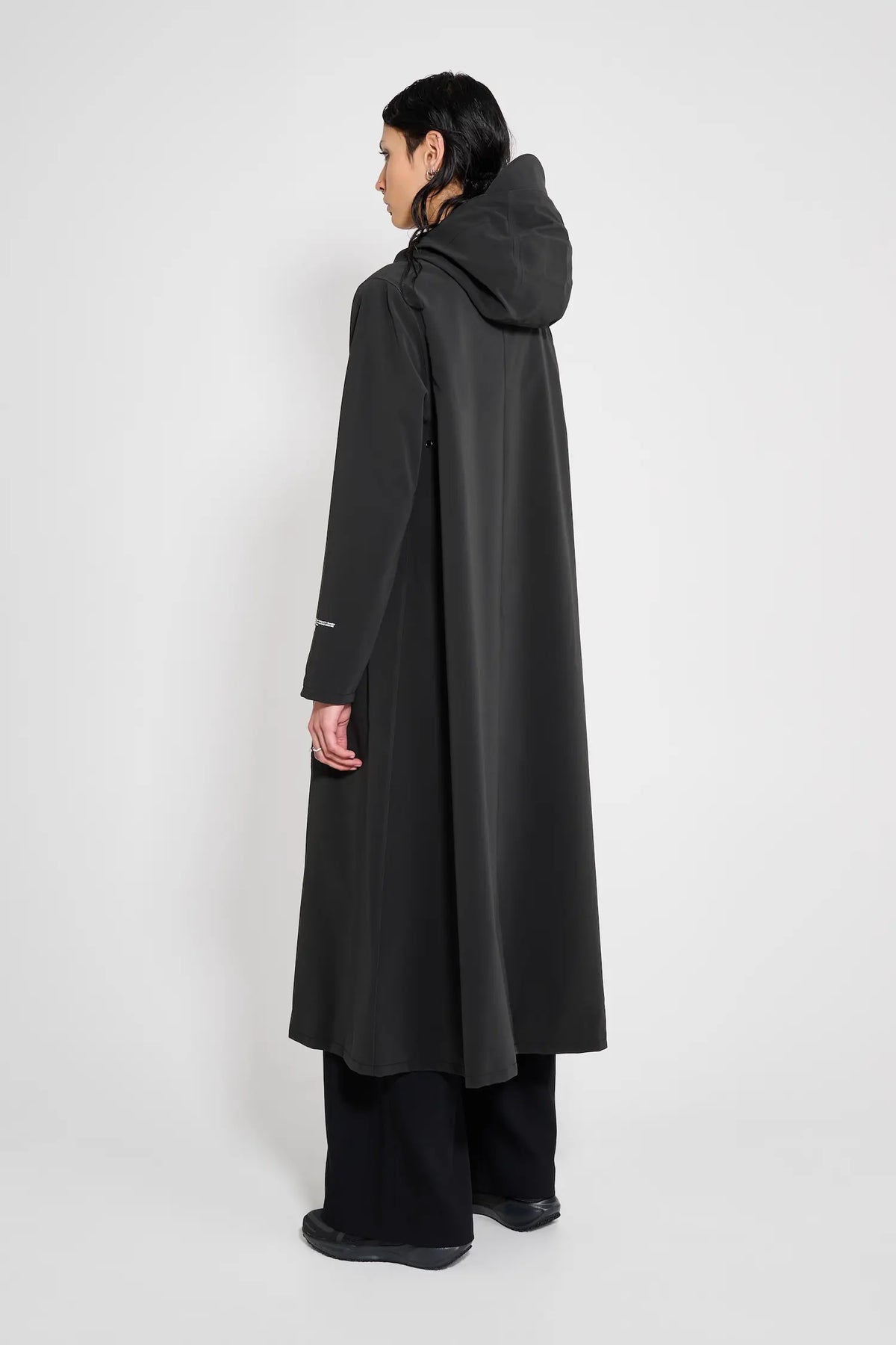 Mosebacke Long Patch Black Raincoat featuring an adjustable hood and A-line silhouette from the back.