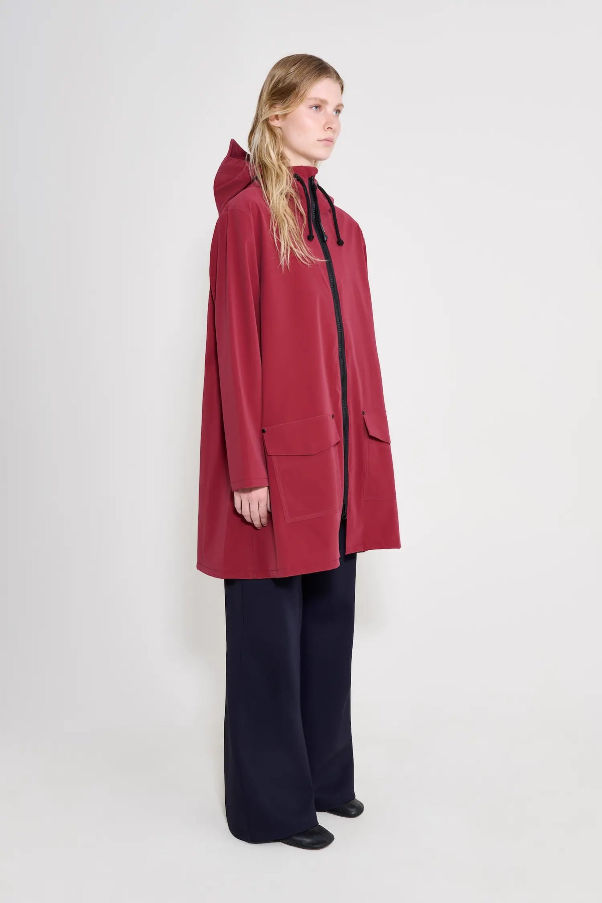 Mosebacke Patch Burgundy Raincoat displayed on a model, showcasing its A-line silhouette and adjustable hood.