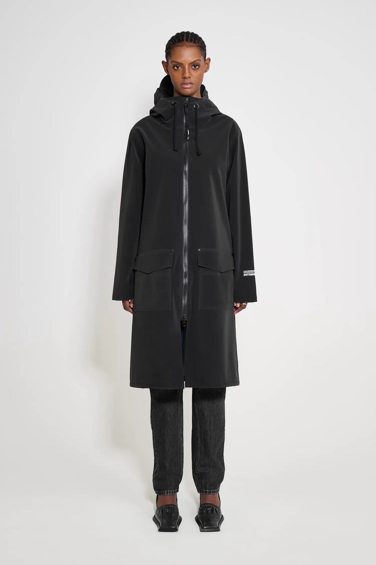 Model wearing the Stockholm Long Patch Black Raincoat, showcasing its straight oversized fit and waterproof features.