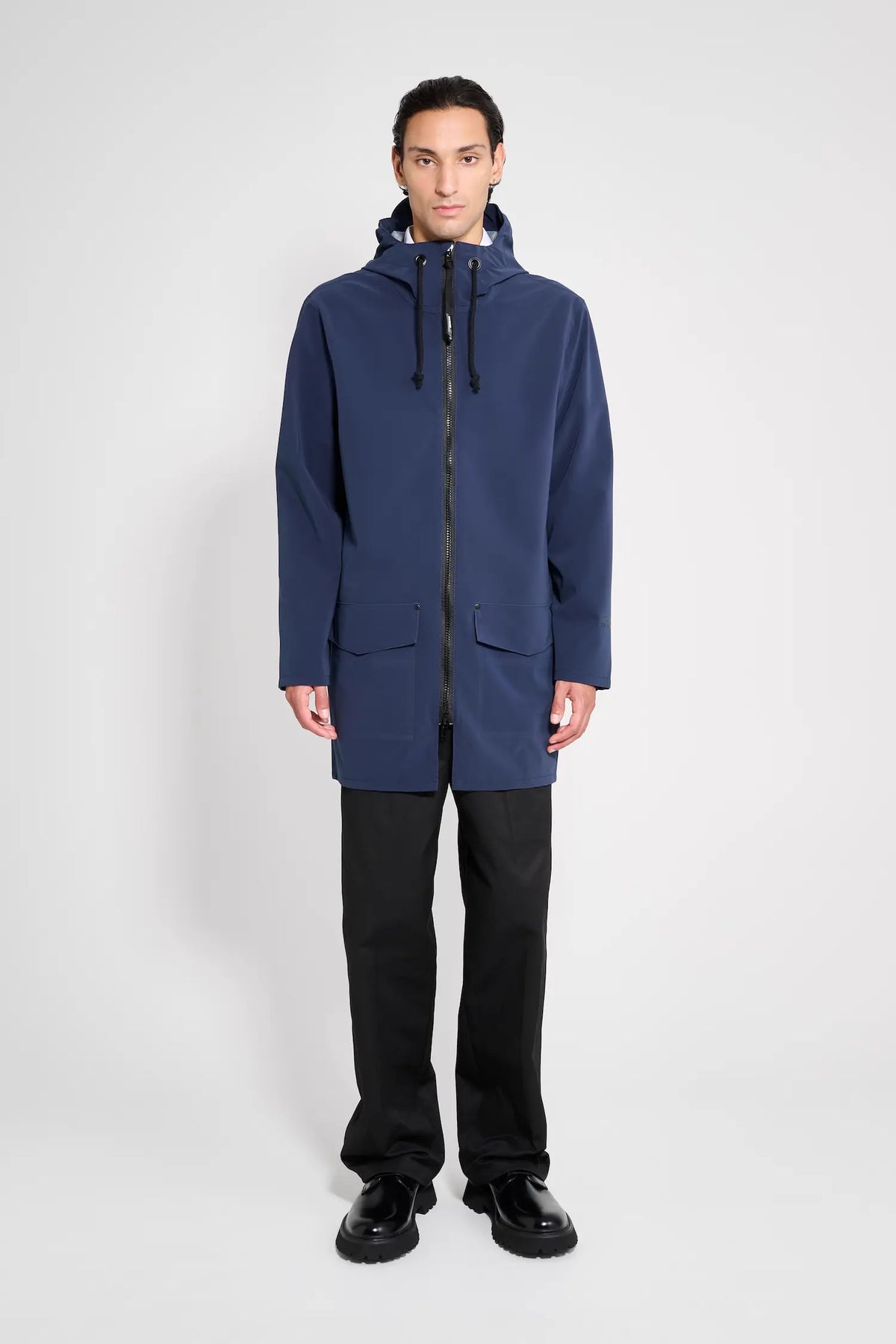 Stockholm Patch Navy Raincoat worn by a model, showcasing its lightweight and waterproof design with adjustable features.