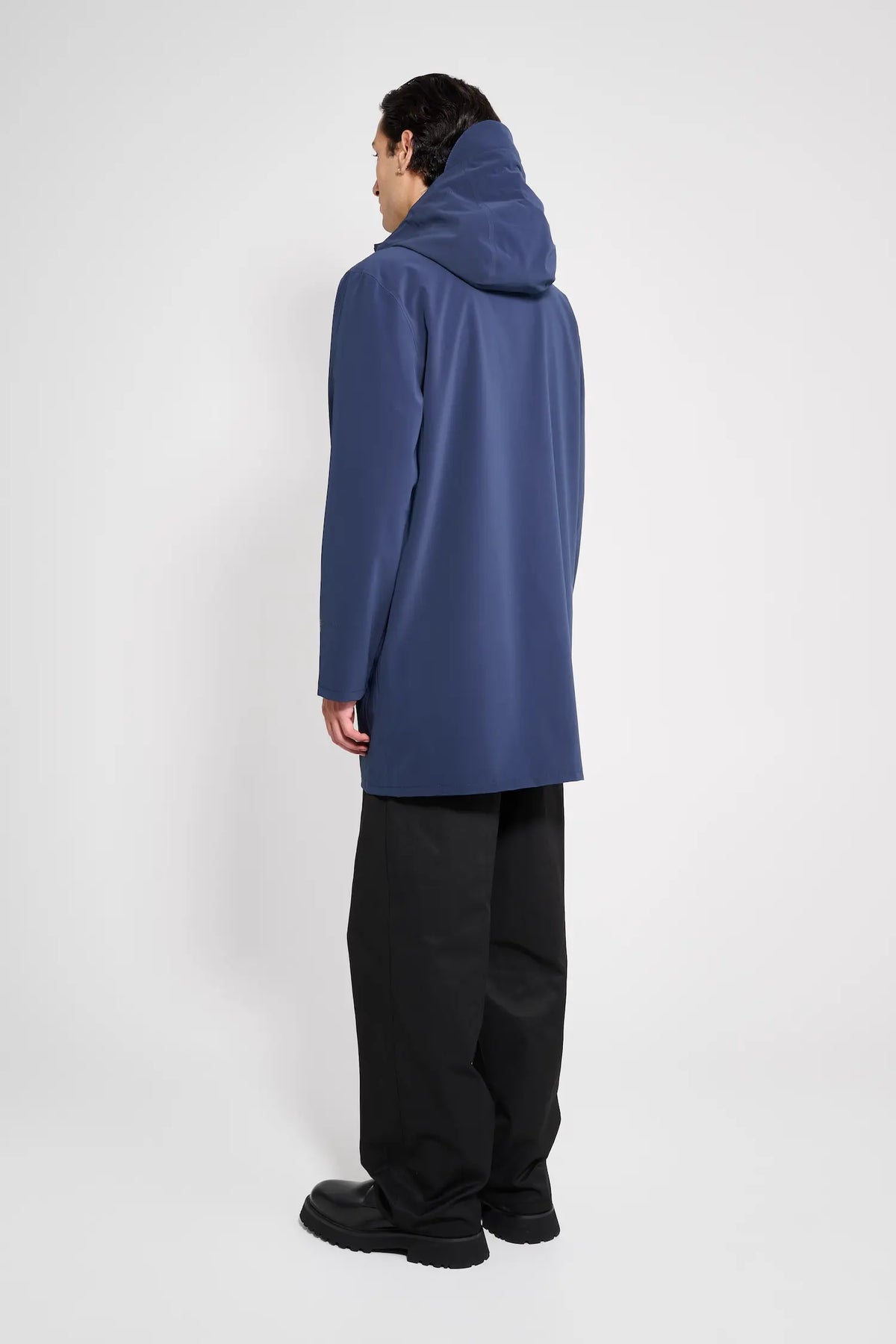 Stockholm Patch Navy Raincoat worn by a model from the back, showcasing its oversized fit and adjustable hood.