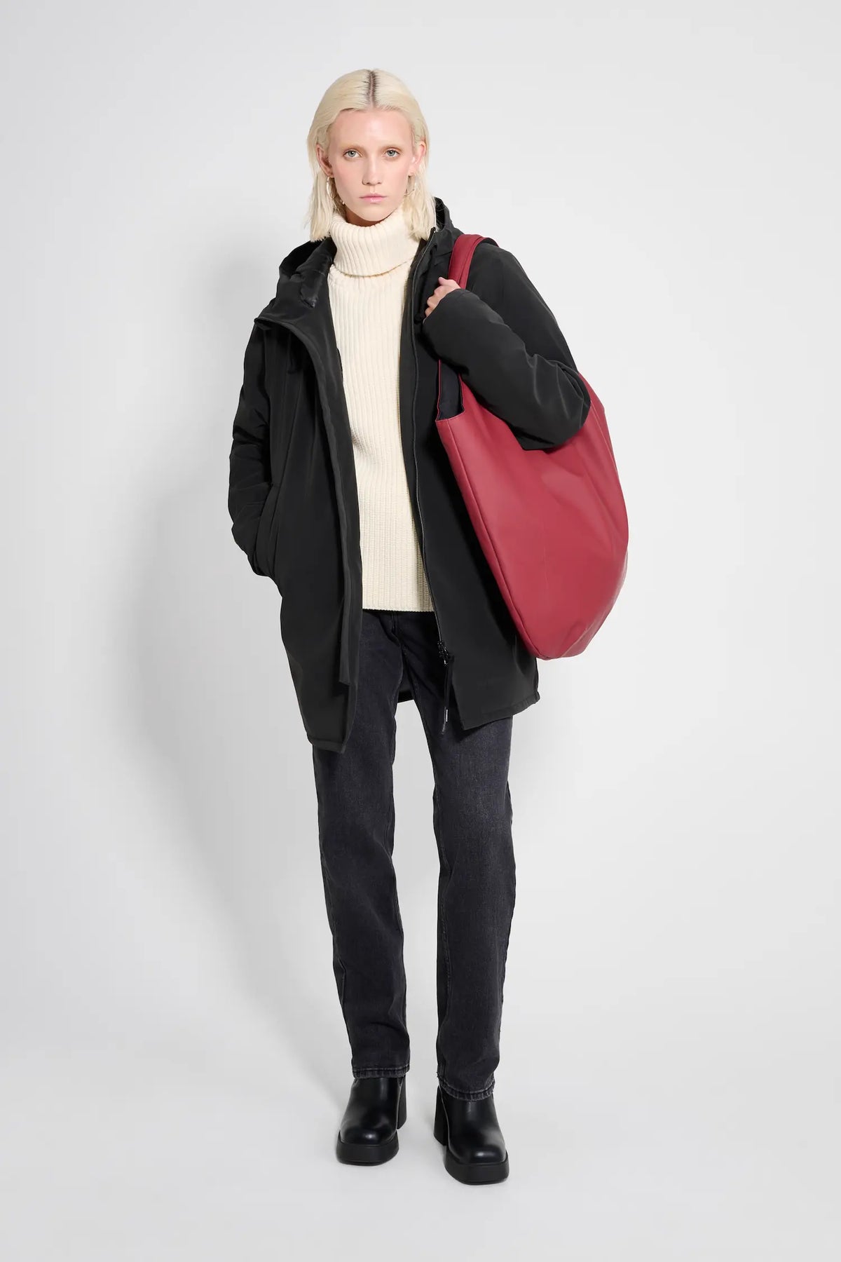 Model wearing Stockholm Matte Black Winter Coat with a red bag, styled for winter fashion.