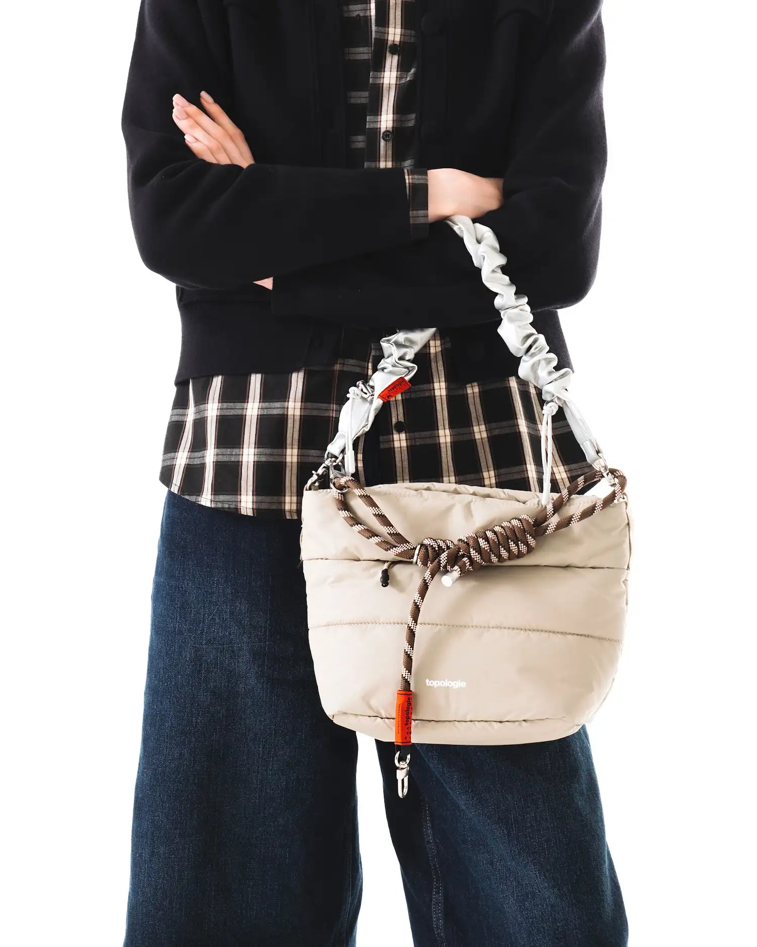 Person holding a Besace Ecru Matt Coated Bag with adjustable strap, showcasing its lightweight design.