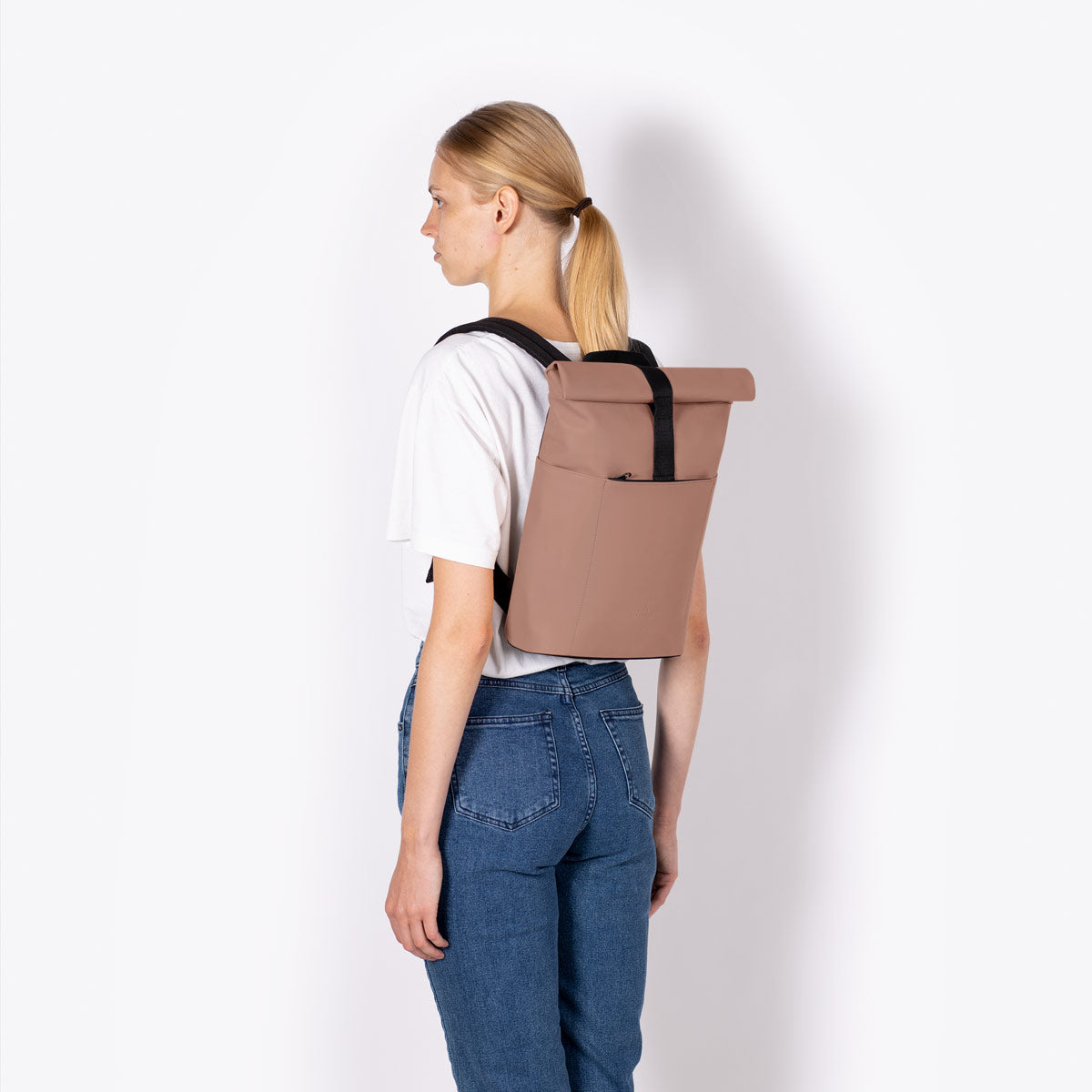 Hajo Macro Lotus Redwood Backpack shown on a model from the back, featuring roll-top closure and padded straps.