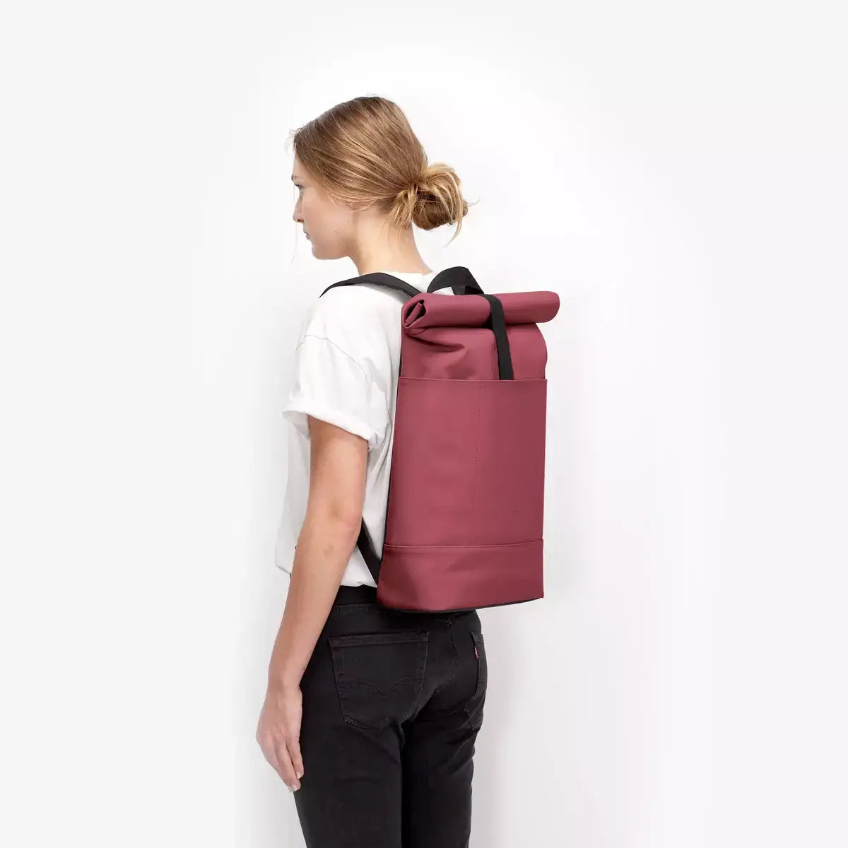 Hajo Lotus Infinity Burgundy Backpack model showcasing side view with roll-top design and padded shoulder straps.