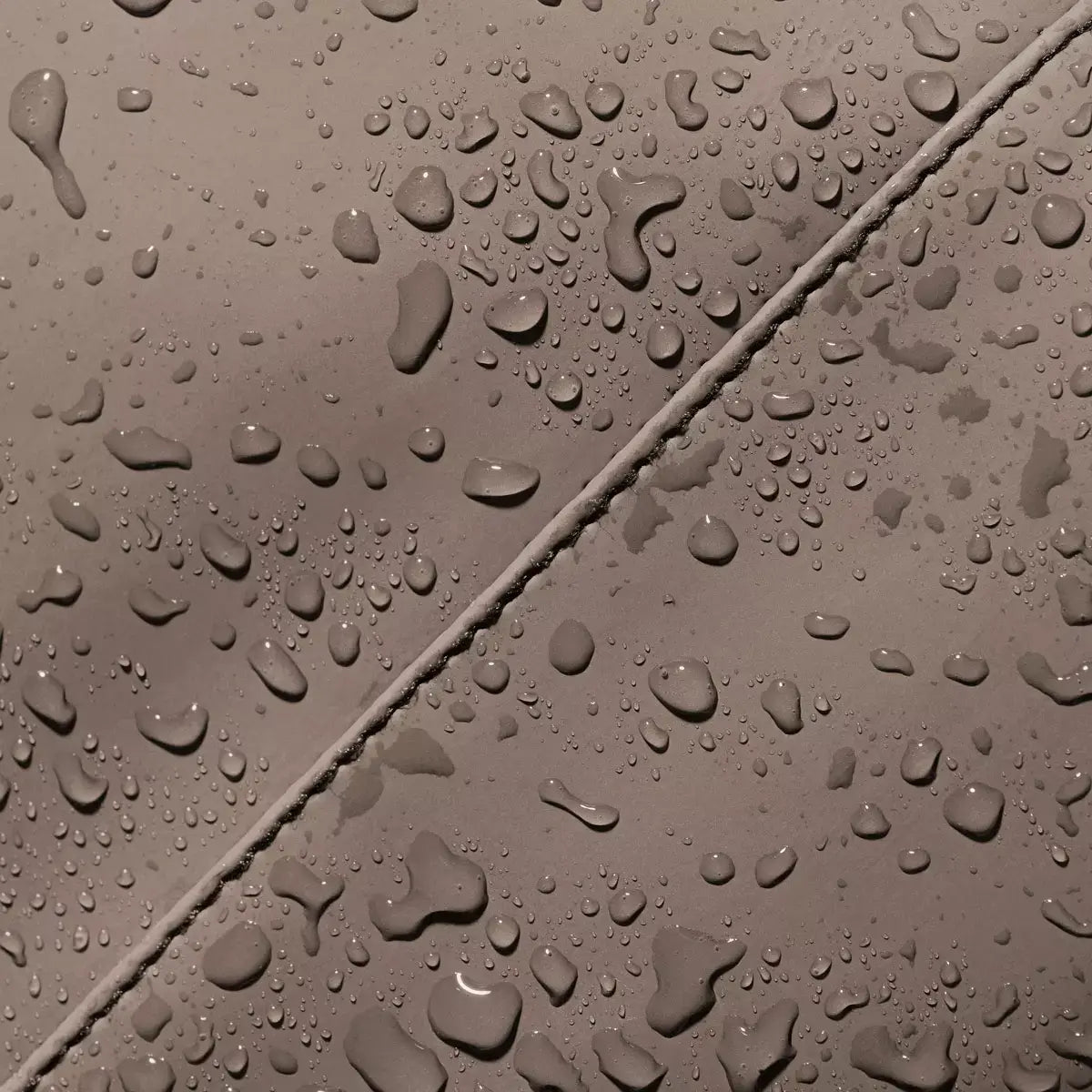 Close-up of water droplets on the Katsu Lotus Infinity Dark Sand Shoulder Bag material, showcasing its water resistant feature.