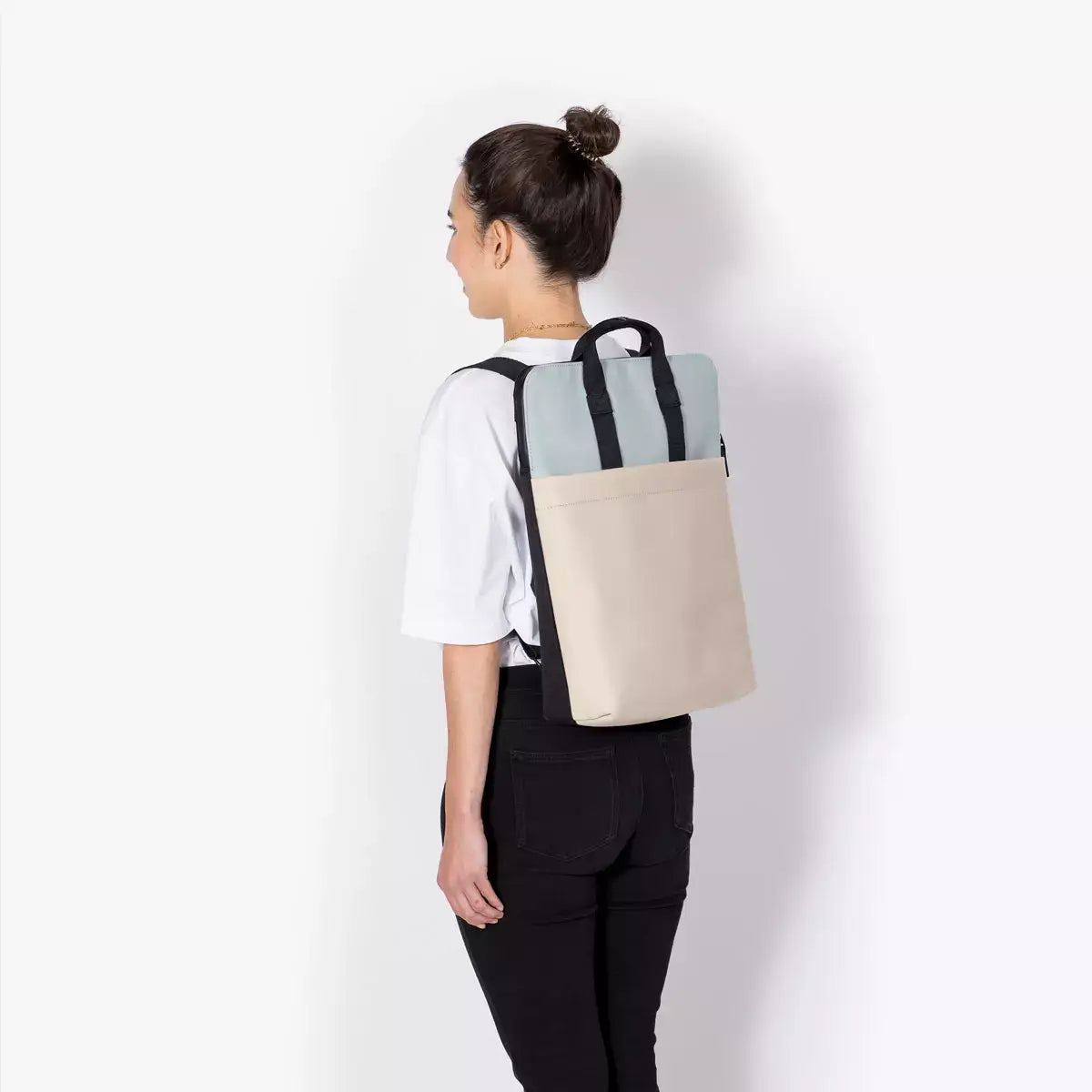 Masao Lotus Infinity Dusty Blue Light Sand Backpack worn on back with a minimalist design and dual function.
