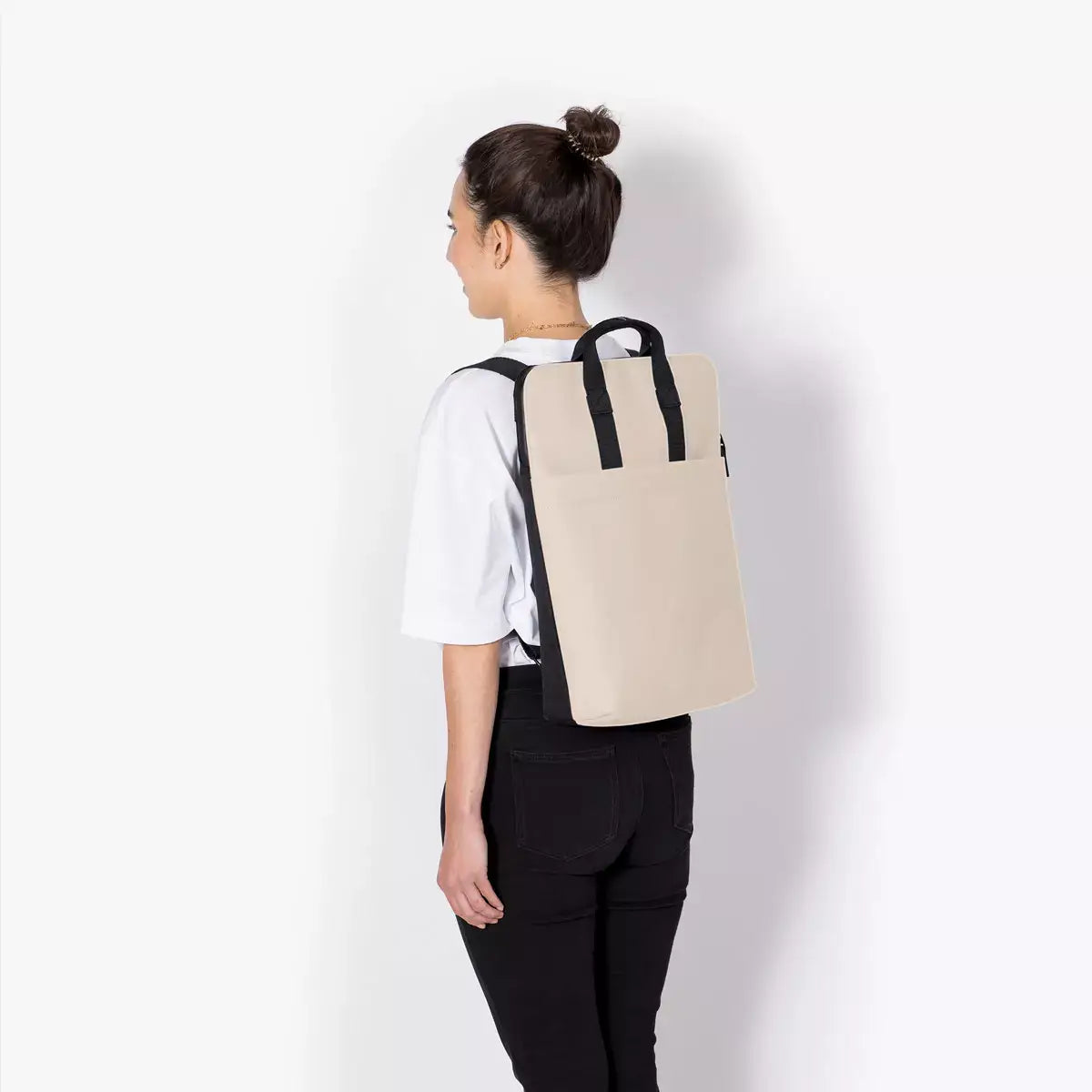 Woman wearing Masao Lotus Infinity Sand Backpack, a stylish and functional backpack and shoulder bag in one.