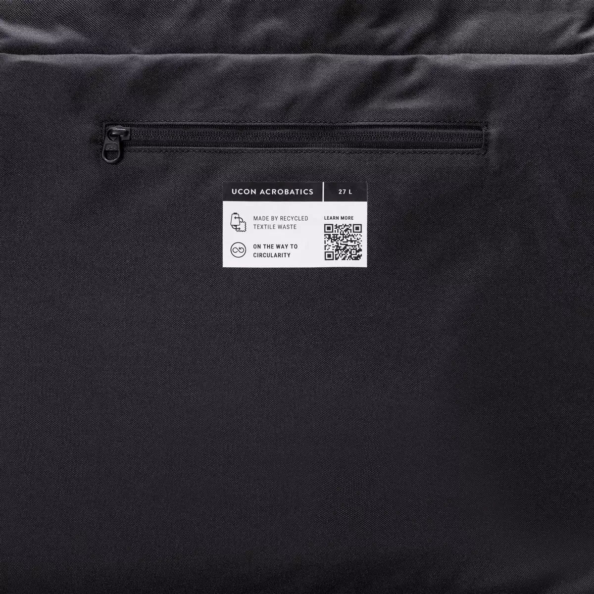 Olivia Large Moss Black Shoulder Bag showing the label with zipper pocket and recycled textile information.