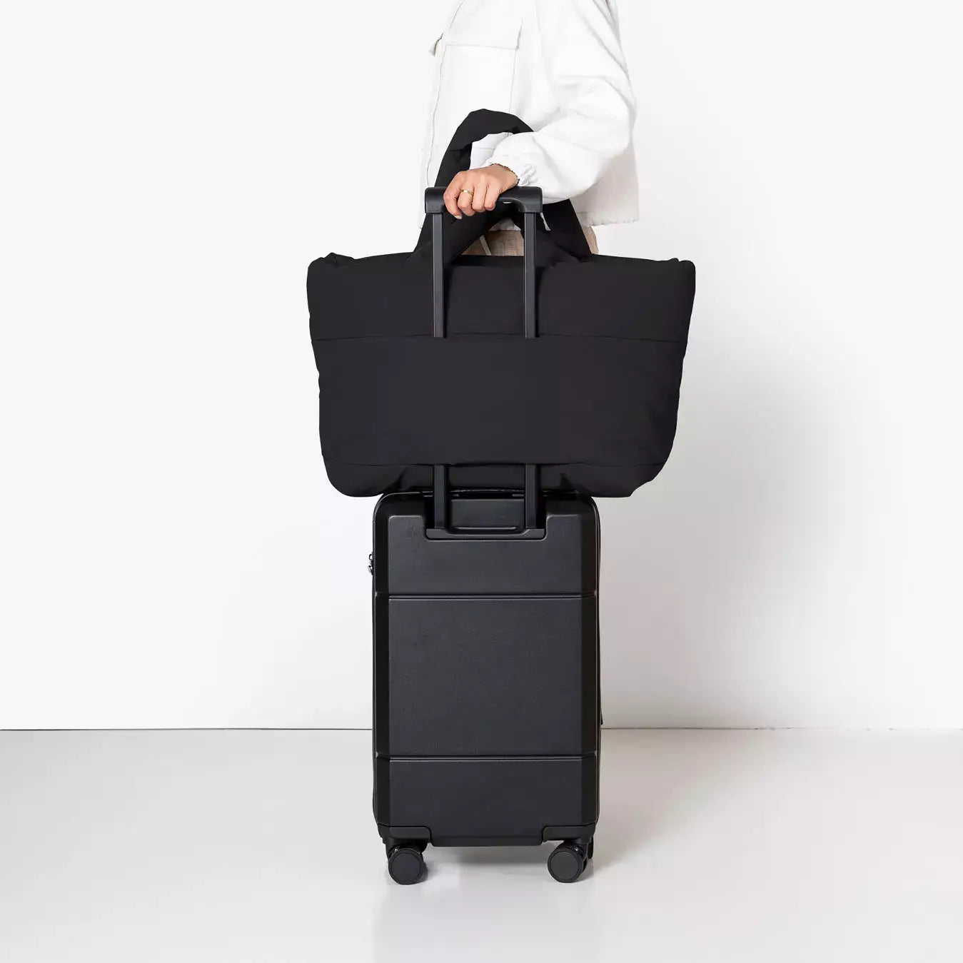 Olivia Large Moss Black Shoulder Bag stylishly placed on top of a black suitcase for travel convenience.