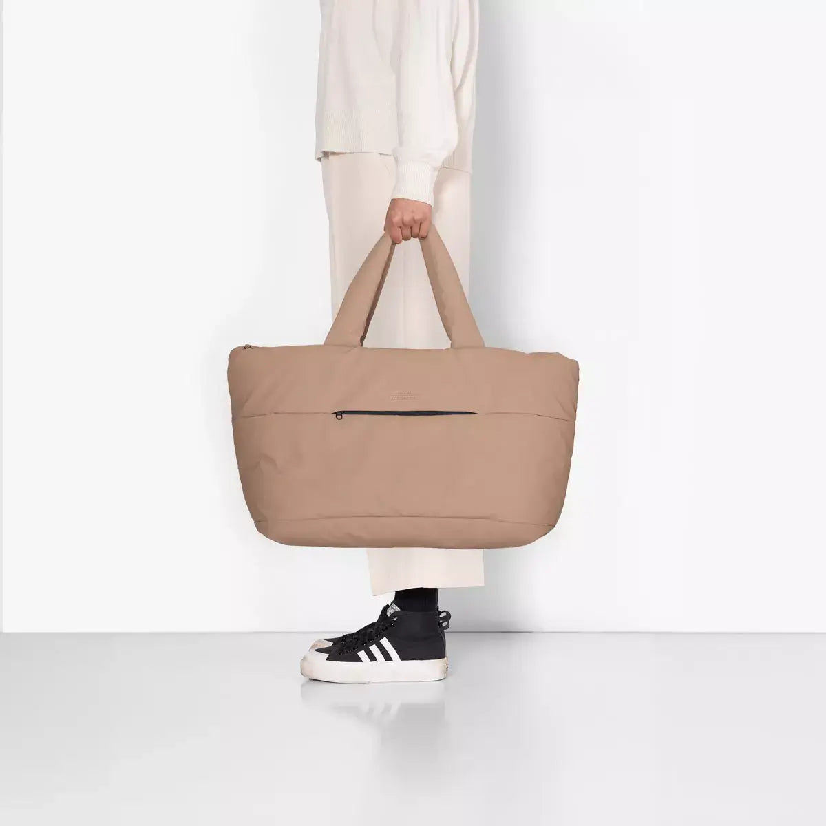 Olivia Large Moss Earth Shoulder Bag shown on a model with a beige color and front zipper pocket.