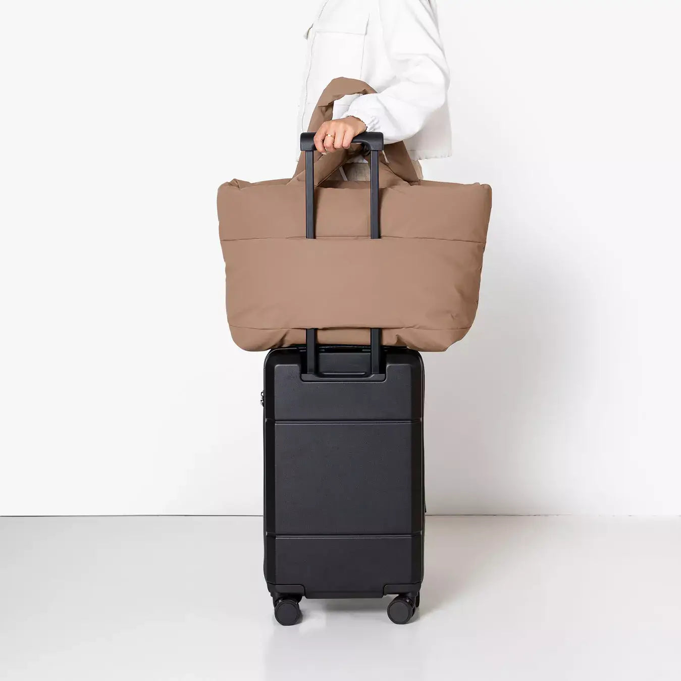 Olivia Large Moss Earth Shoulder Bag being carried on a black trolley suitcase, showcasing its travel-friendly design.