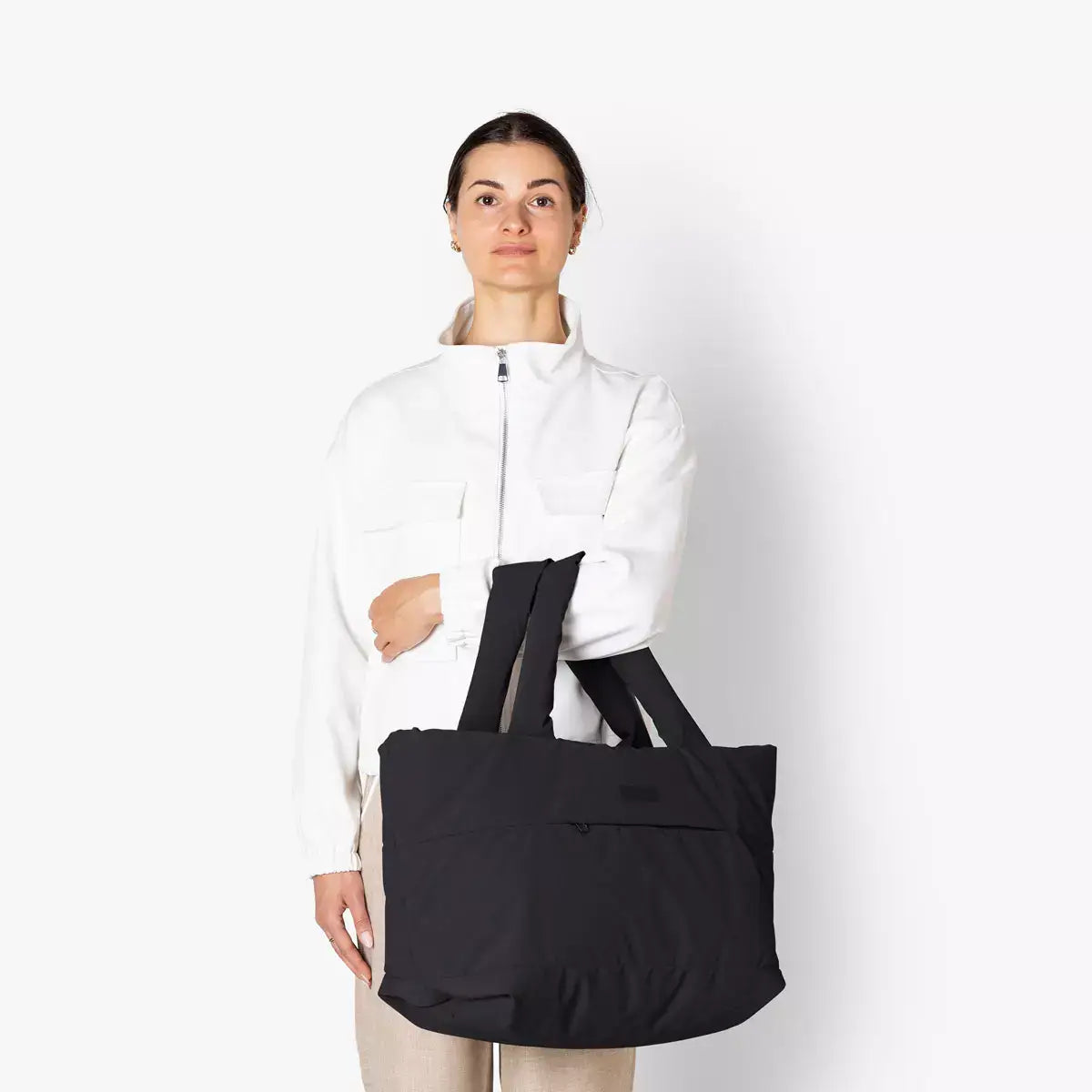 Olivia Medium Moss Black Shoulder Bag being held by a model in a white jacket, showcasing its spacious design.