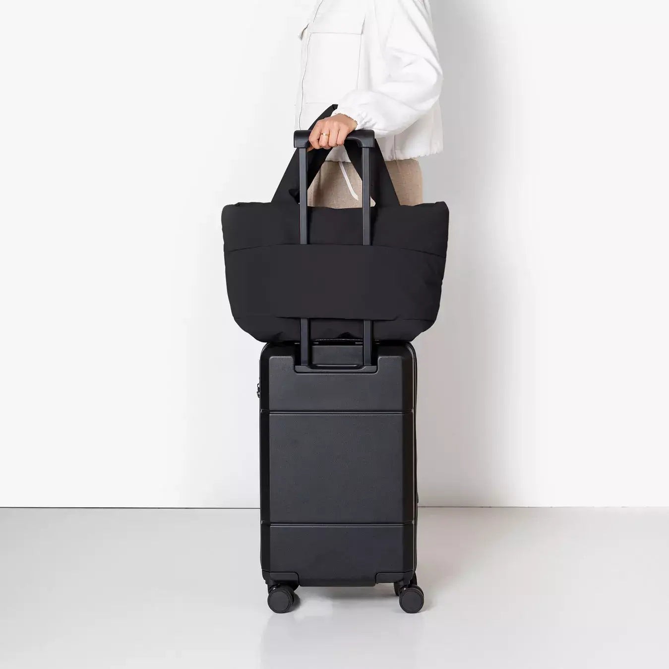 Olivia Medium Moss Black Shoulder Bag on top of a black suitcase, showcasing its travel-friendly design.