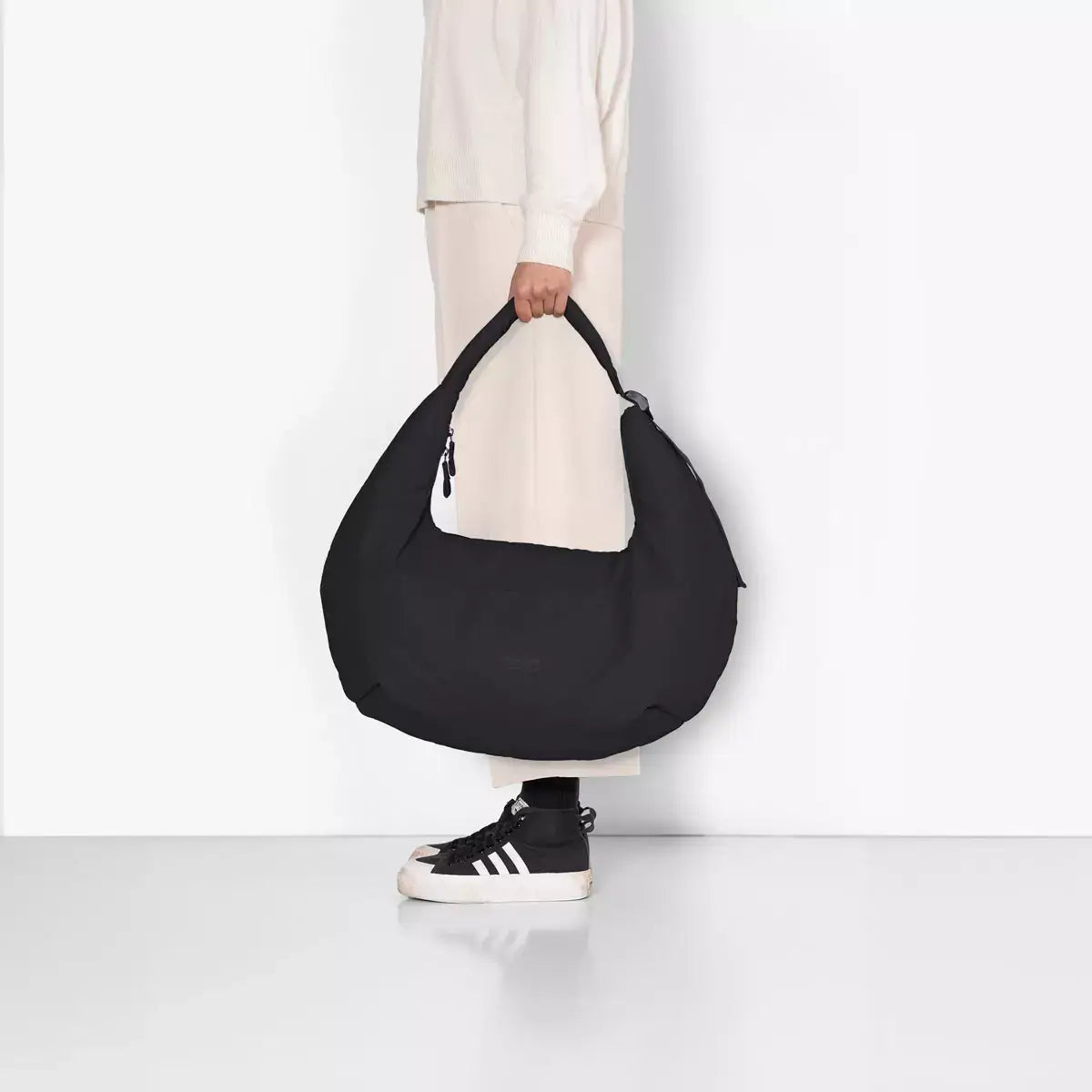 Shota Large Moss Black Shoulder Bag being held by a person in stylish attire, showcasing its large puffer design.