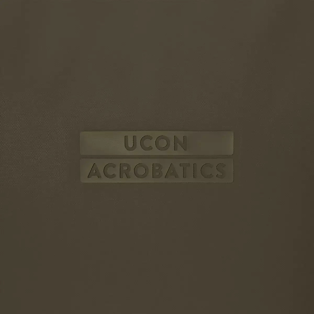 UCON ACROBATICS logo on a dark olive background, stylish and modern branding for bags and accessories.