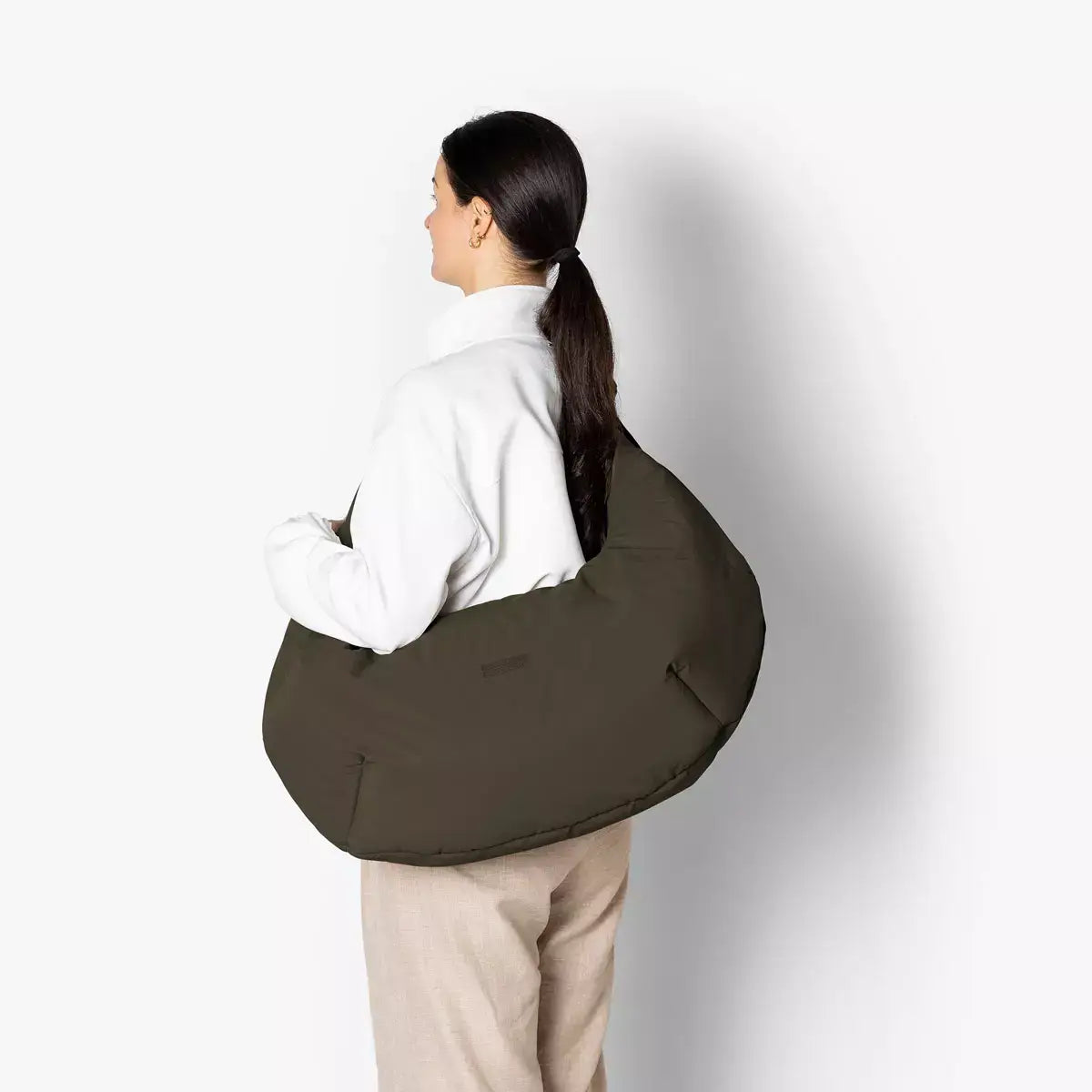 Shota Large Moss Olive Shoulder Bag worn by a model, showcasing its large puffer design and water-resistant material.