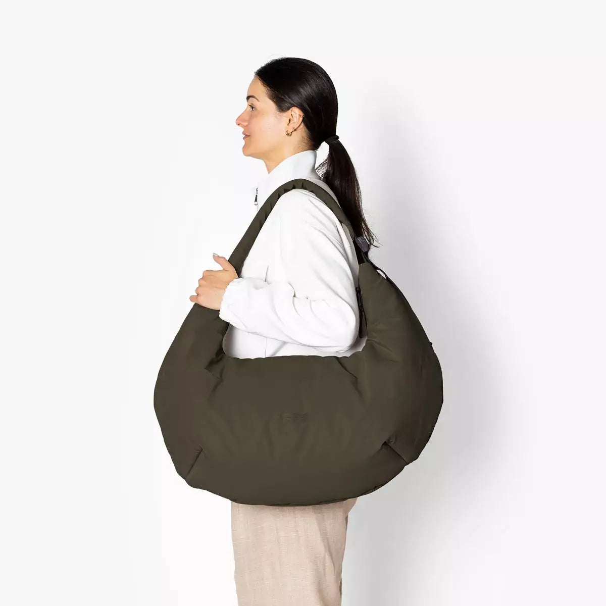 Shota Large Moss Olive Shoulder Bag worn by a woman, showcasing the large puffer design and adjustable strap.