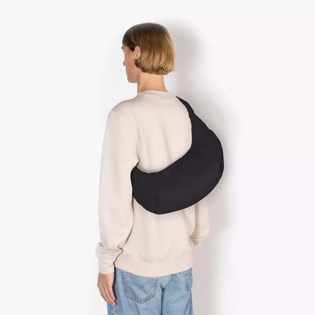 Shota Medium Moss Black Shoulder Bag worn over a person's shoulder, showcasing its sleek design and water-resistant features.